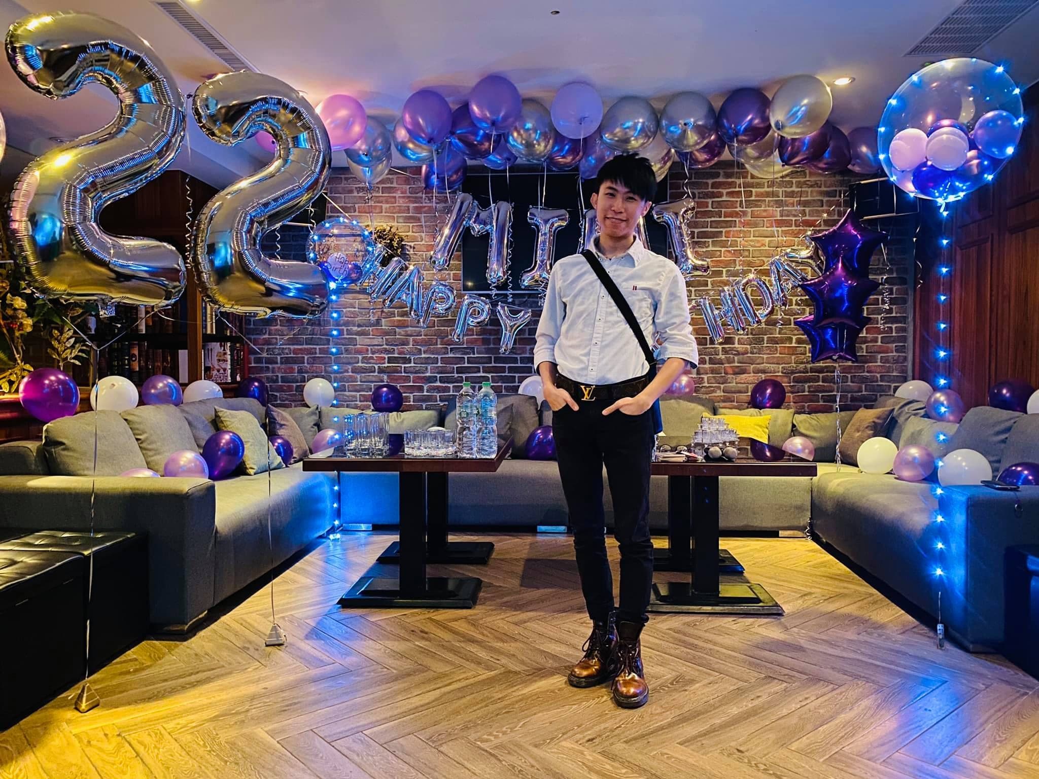 柯男站在紫銀色生日包廂中央，身後是字母氣球與數字 22