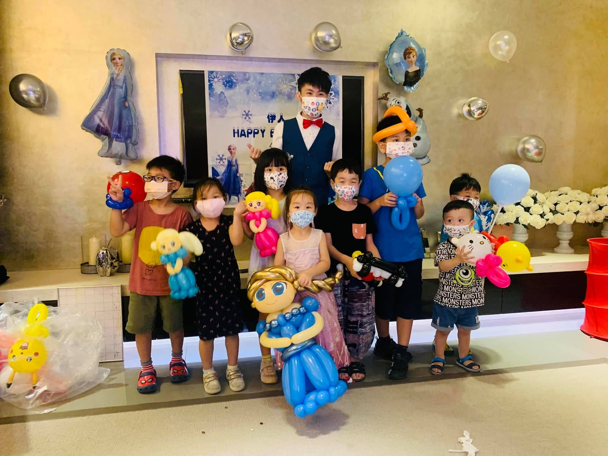 冰雪奇緣生日派對背板前，小朋友拿著艾莎人偶與造型氣球合照