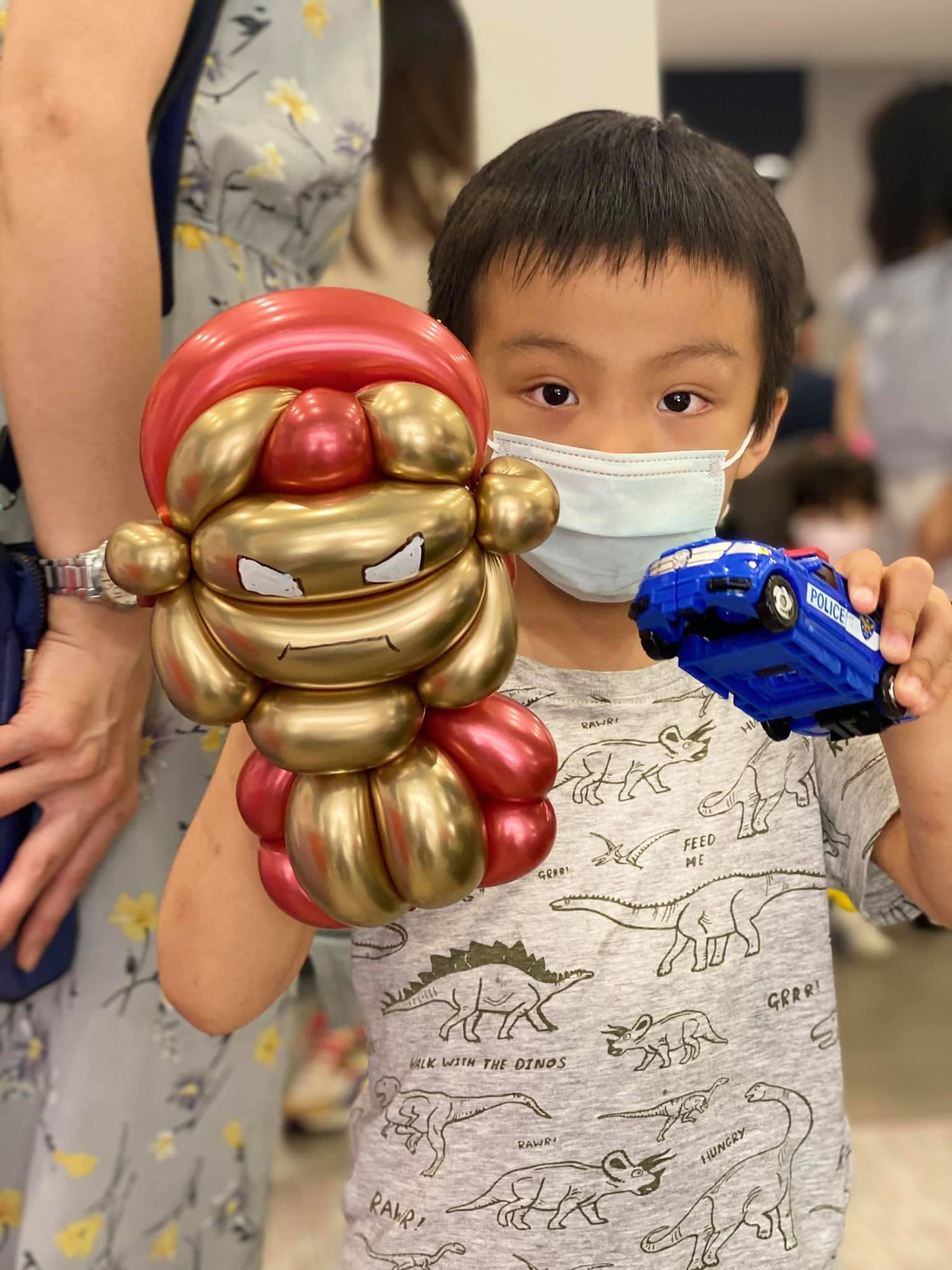 小男孩拿著金紅色鋼鐵人頭盔造型氣球和玩具警車