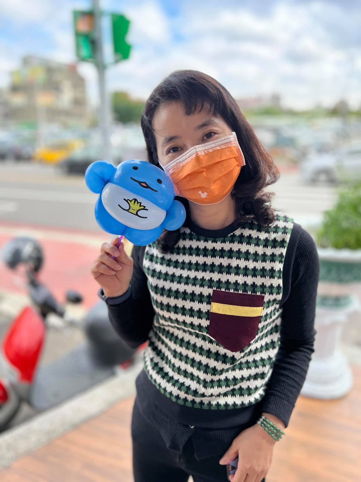 媽媽拿著藍色圓胖、肚子畫黃色皇冠的造型氣球