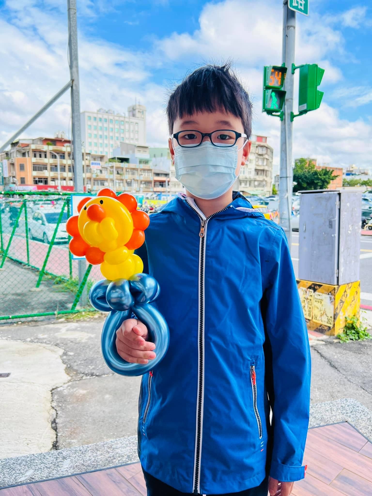 戴眼鏡的男孩拿著獅子頭配藍色護手的寶劍氣球