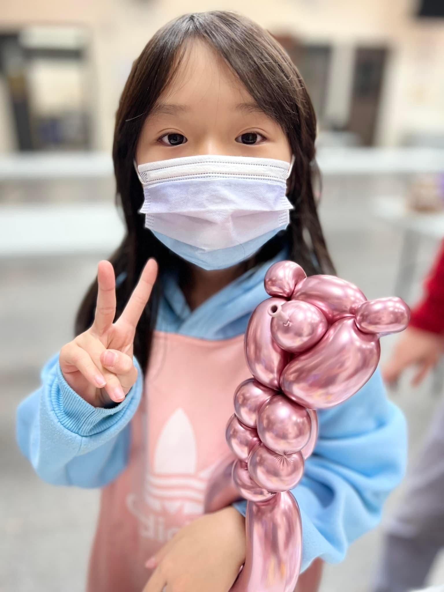 女孩比 YA 拿著玫瑰金色的貴賓狗造型氣球