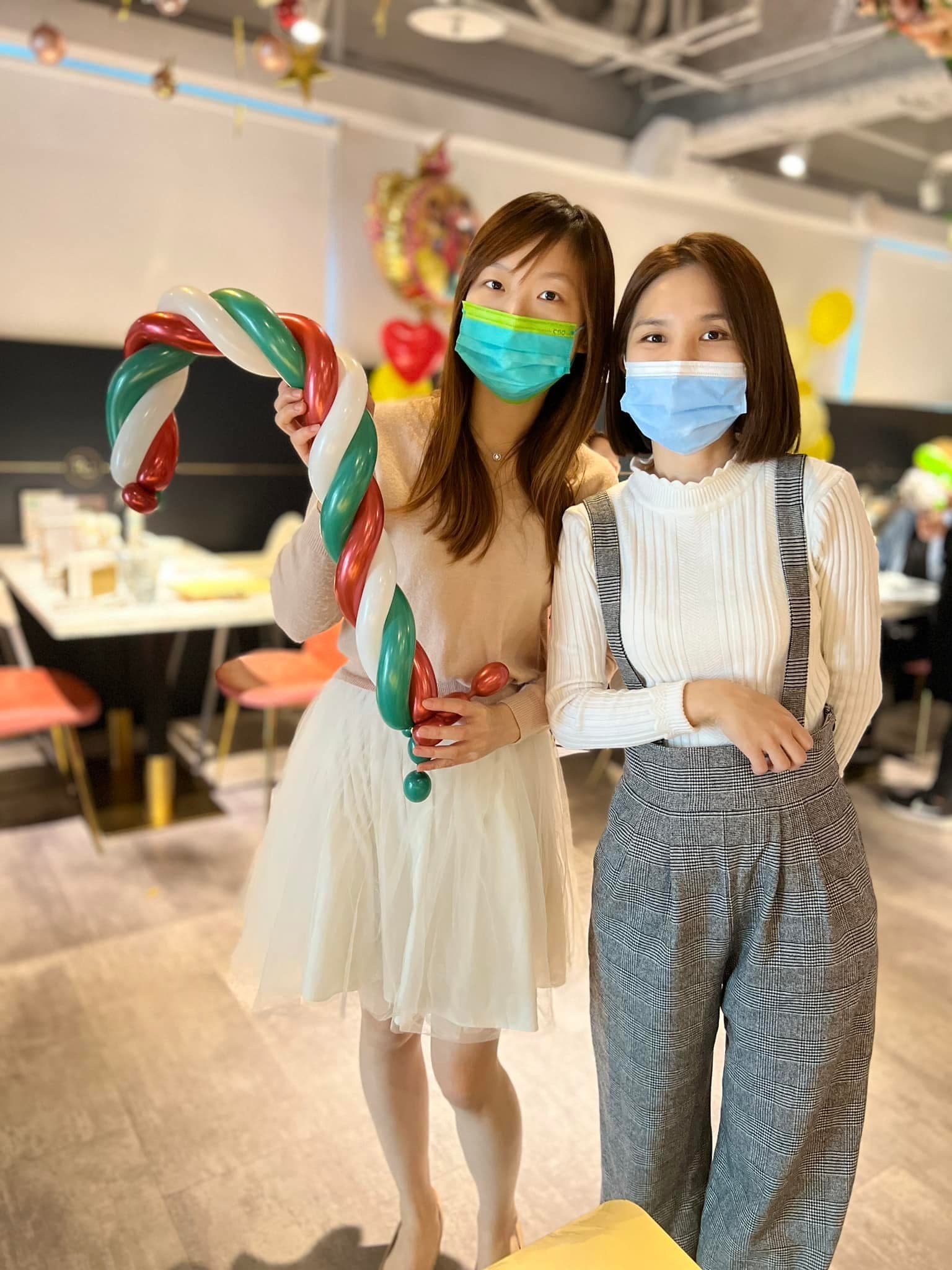 兩位賓客拿著紅綠白配色的拐杖糖造型氣球合照