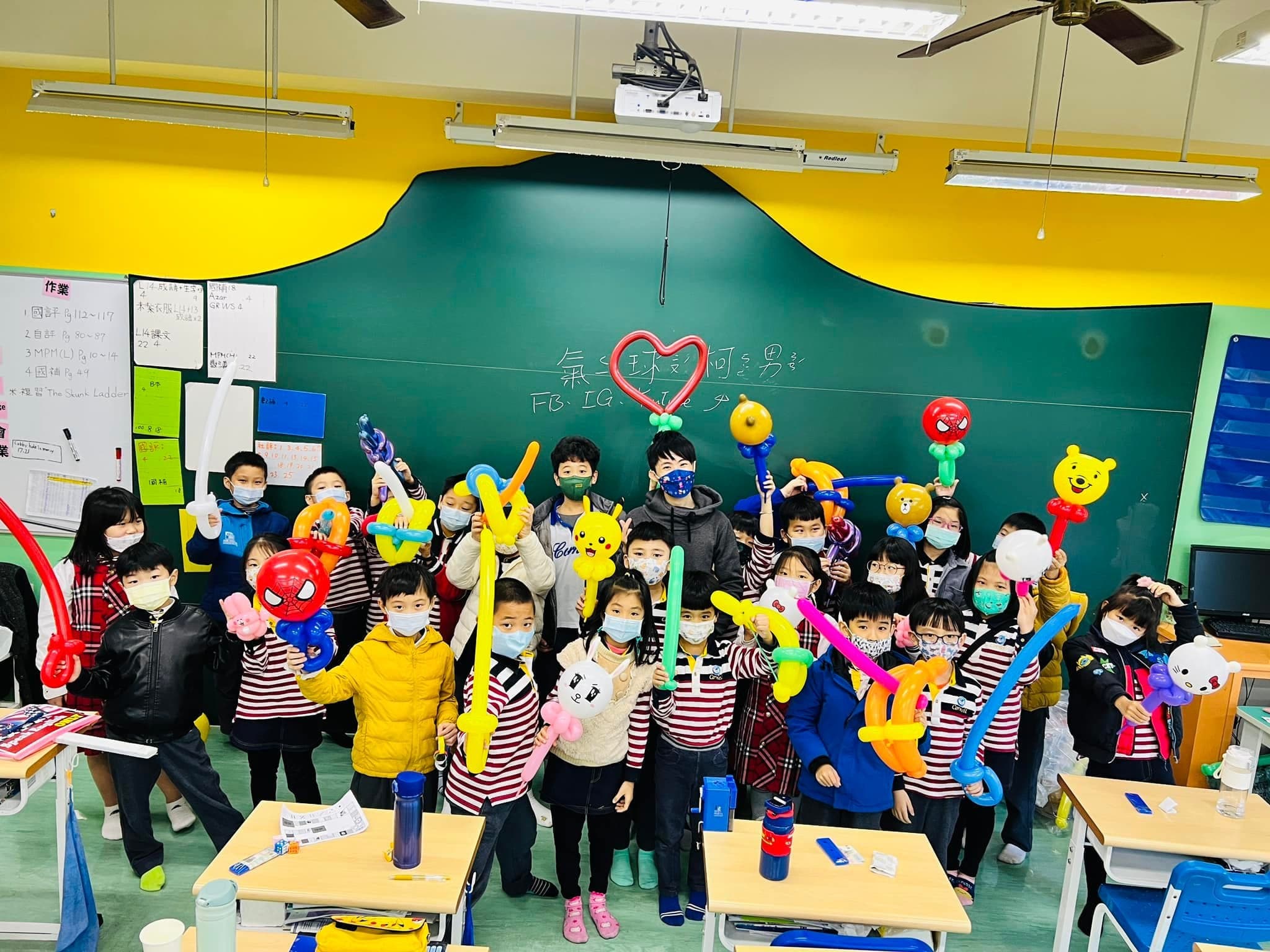 康萊爾魔術課學生在教室舉著造型氣球合照，黑板上畫著愛心