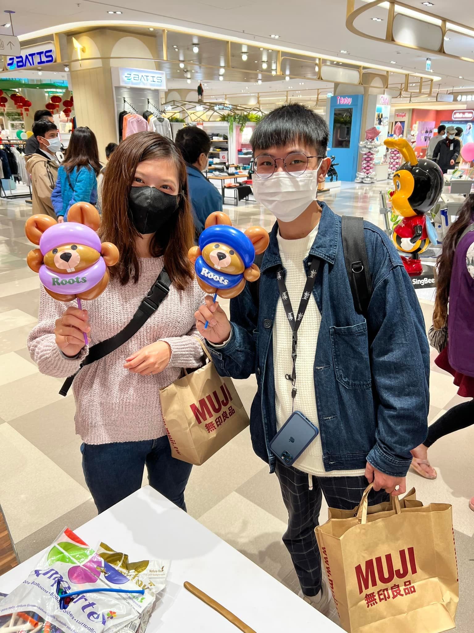 兩位大人顧客各拿一隻紫帽與藍帽海狸寶寶氣球