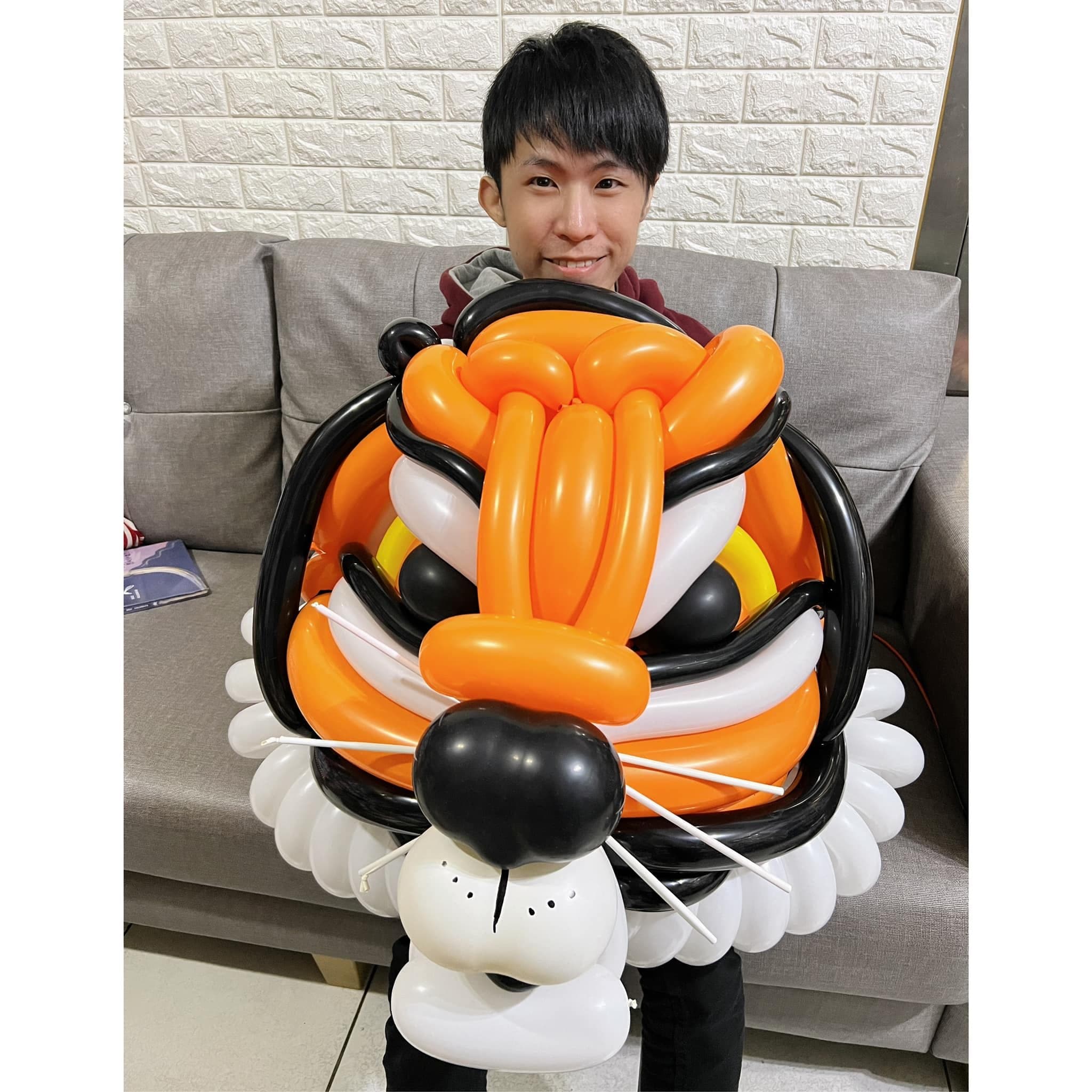 柯男抱著橘黑白配色的大型老虎頭造型氣球