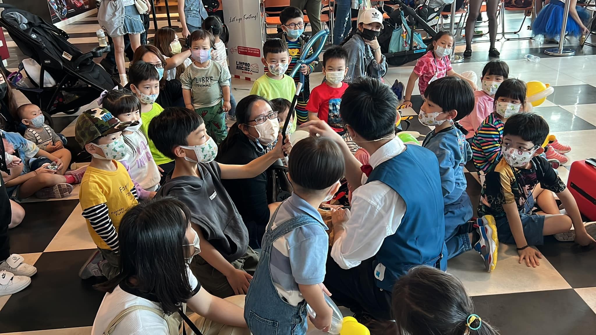 小朋友坐在黑白格地板上，等我現場折造型氣球