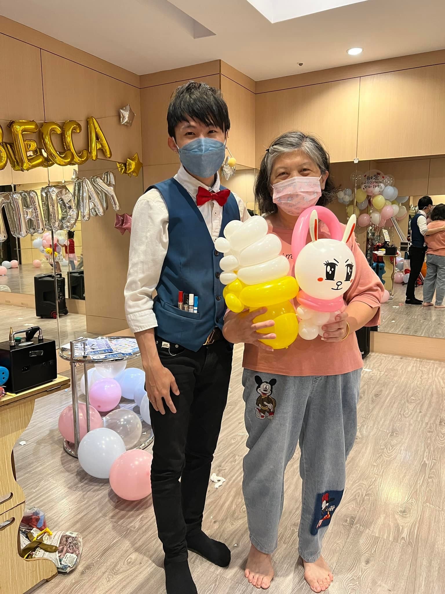 長輩拿著冰淇淋與白色兔子造型氣球和柯男合照
