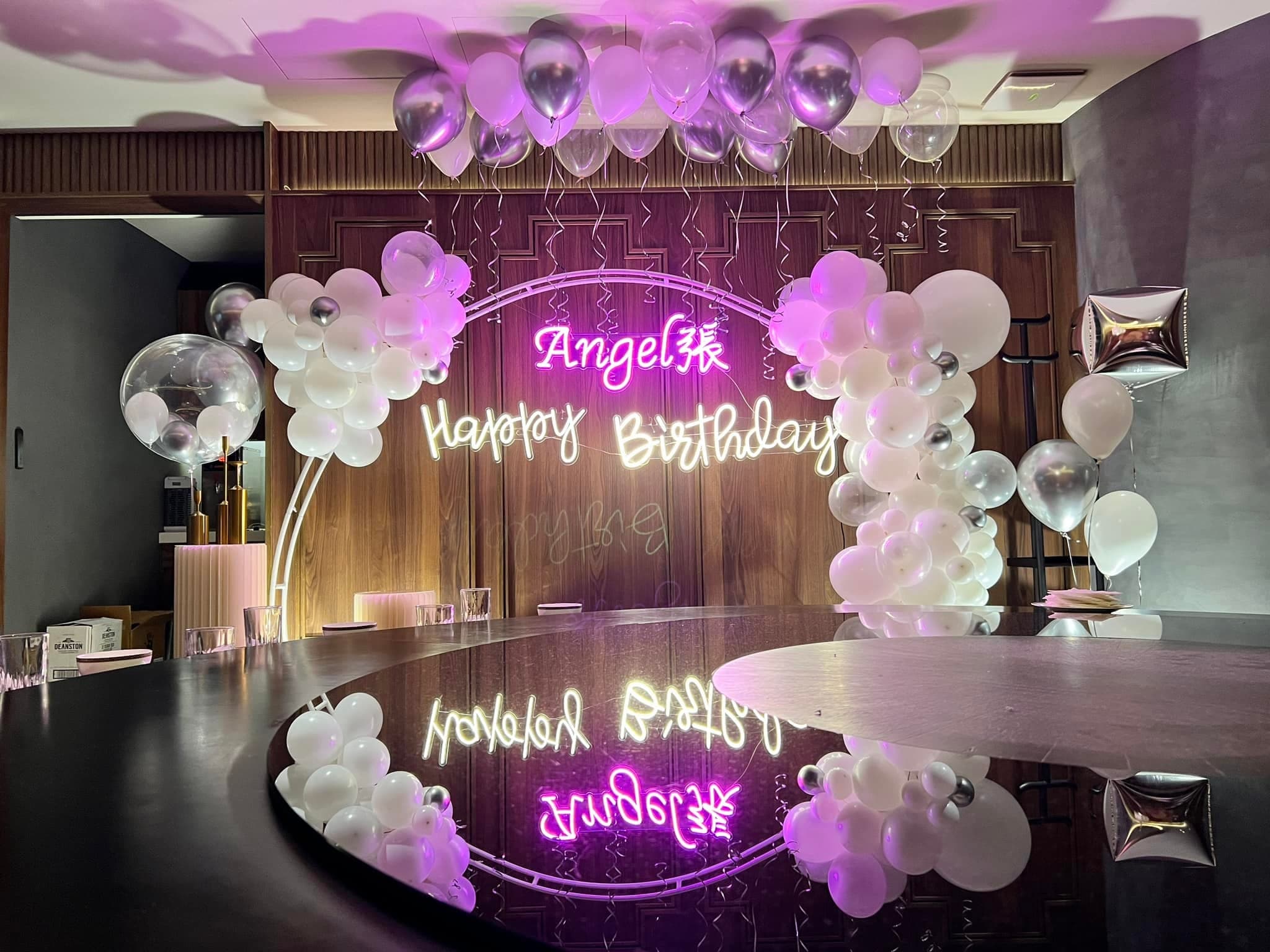 白銀半拱形氣球與霓虹燈字生日背景，倒映在包廂黑色圓桌上