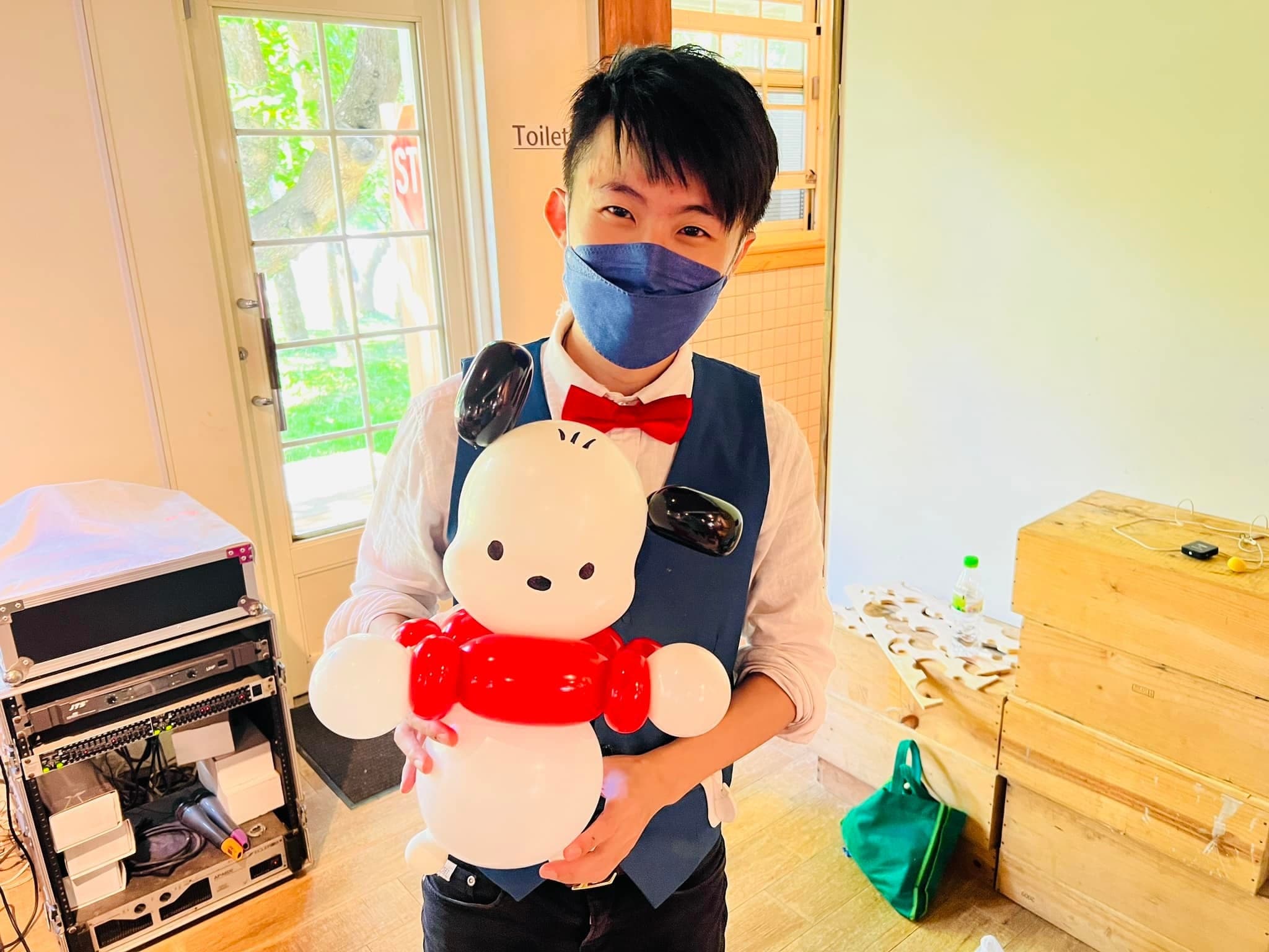 柯男抱著白色身體、紅色圍巾的帕恰狗造型氣球