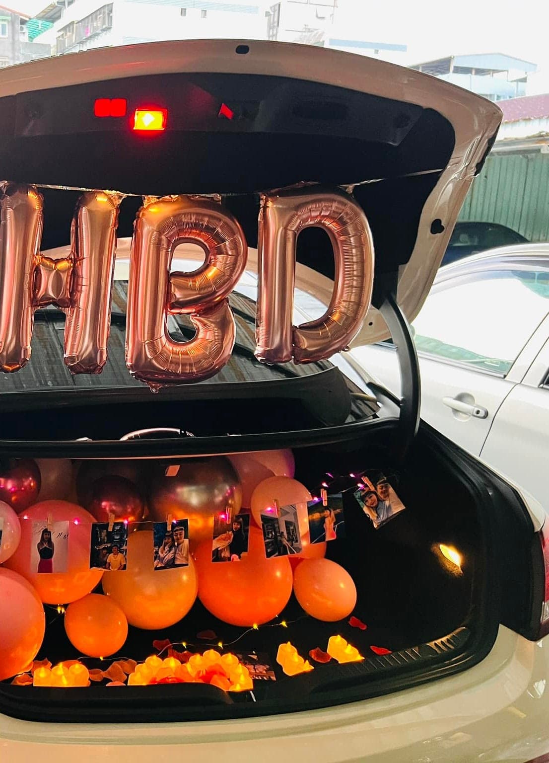 後車廂掛著玫瑰金 HBD 字母氣球,車廂內鋪滿粉橘色氣球與燭光