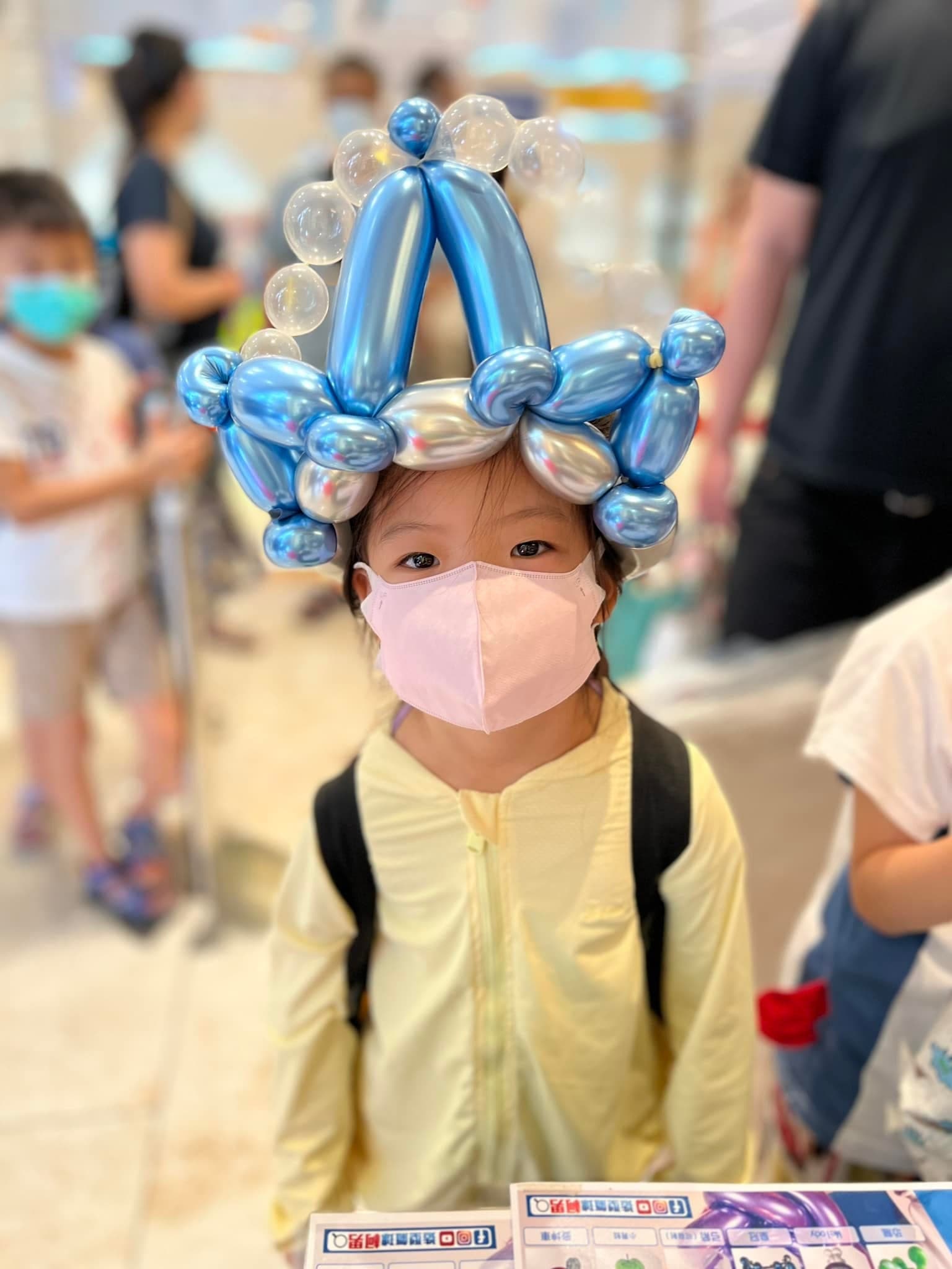 小女孩頭戴銀藍色的皇冠氣球帽