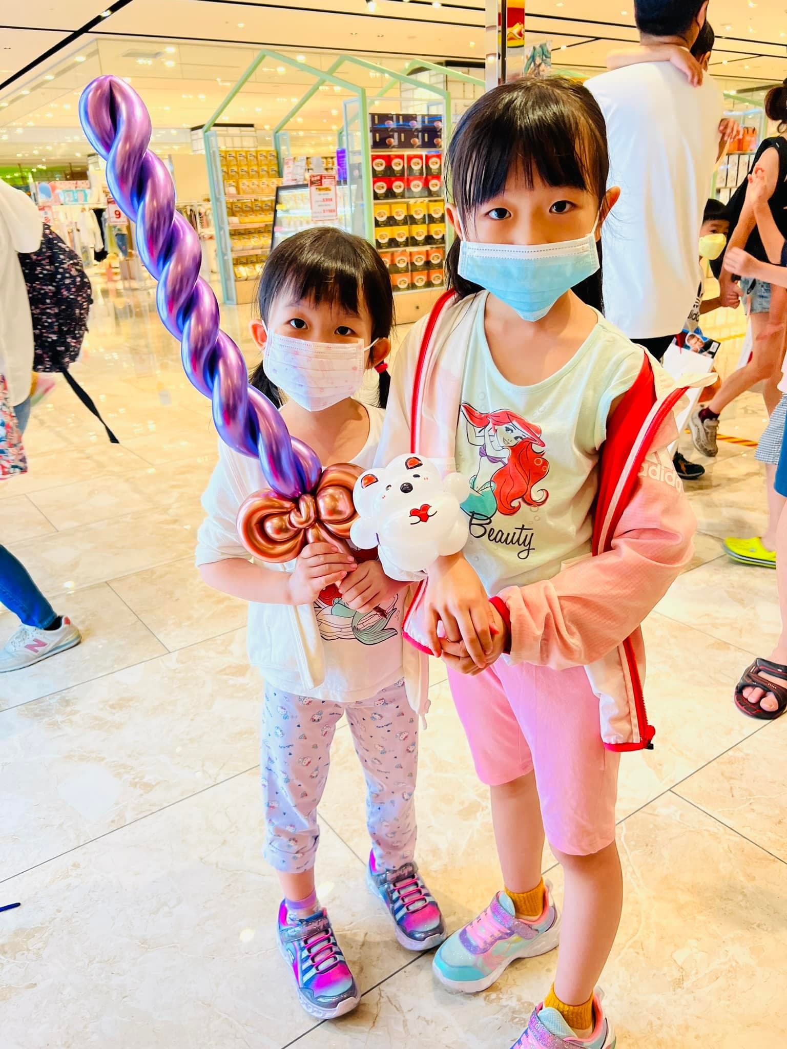 兩個女孩拿著紫色螺旋寶劍和白色小動物氣球