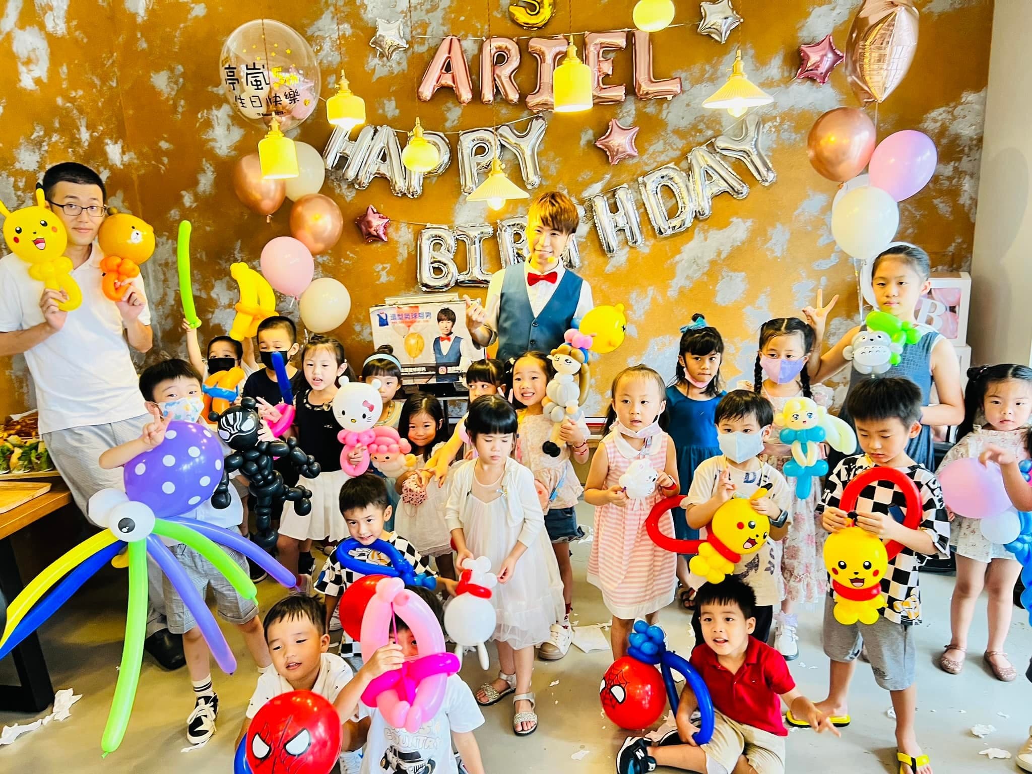 孩子們拿著章魚、皮卡丘、蜘蛛人等造型氣球，在生日牆前大合照