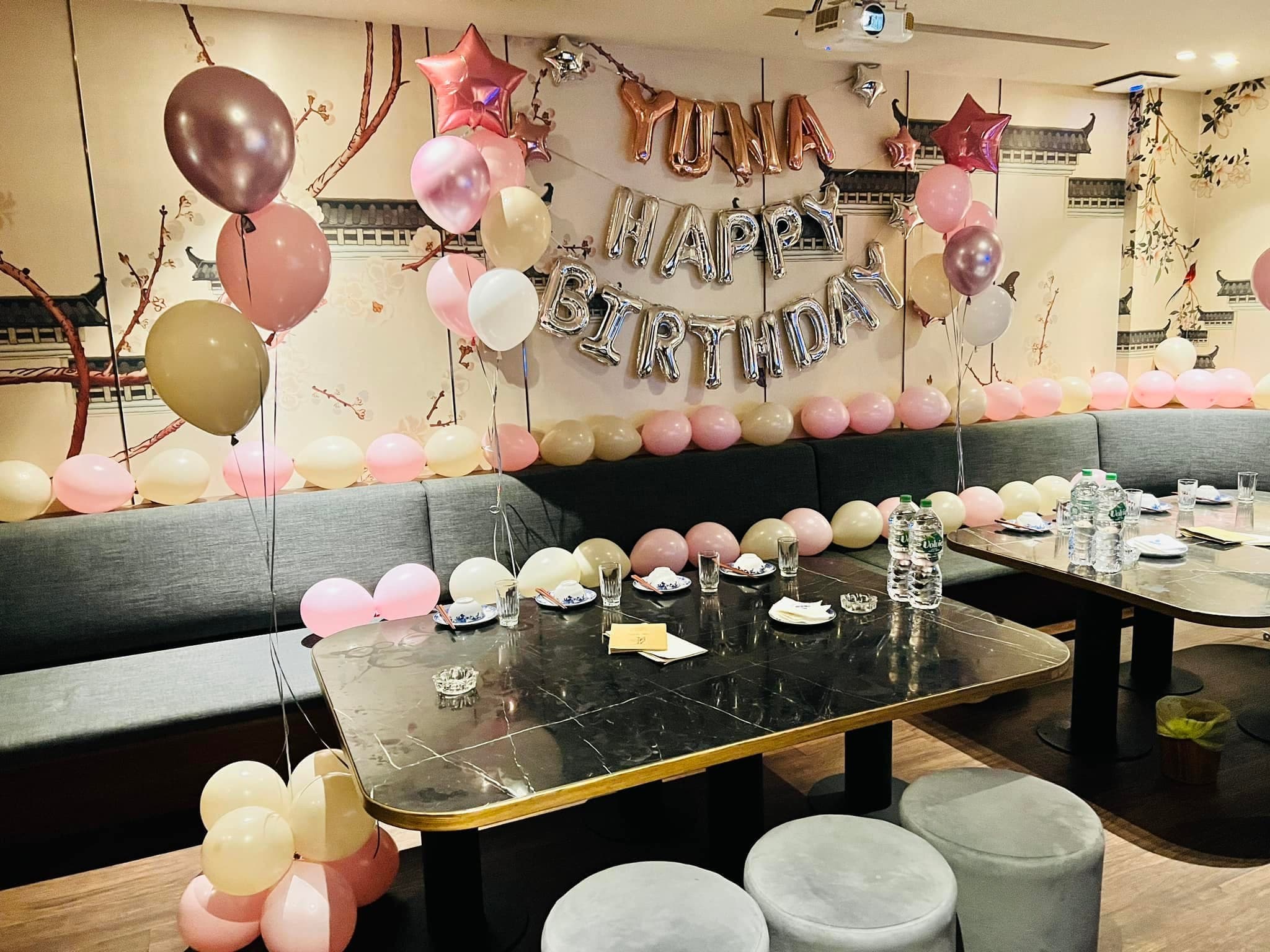 從餐桌望向生日主牆,桌腳旁立著粉色小氣球束