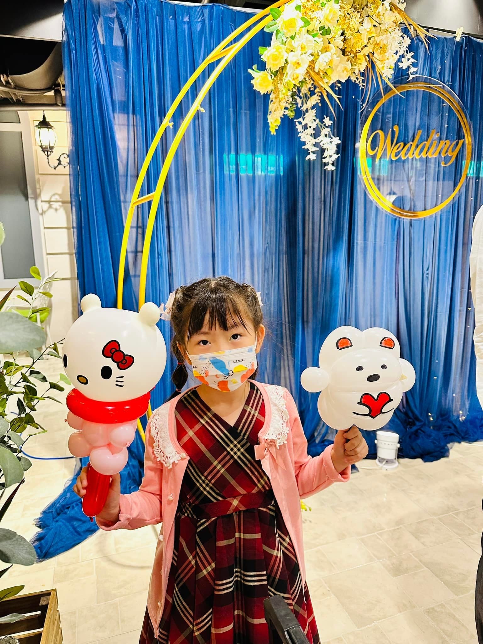 小女孩一手拿 Hello Kitty 氣球，一手拿抱著紅色愛心的白色小熊氣球