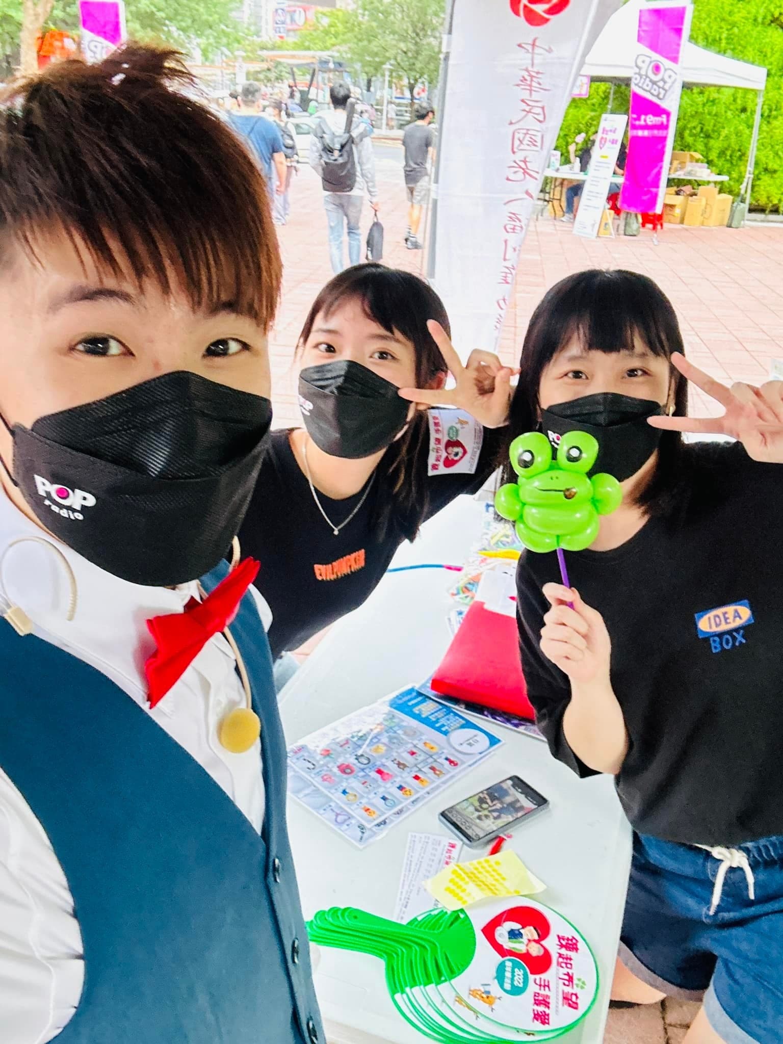 我與兩位工作人員自拍，其中一人拿著綠色青蛙造型氣球