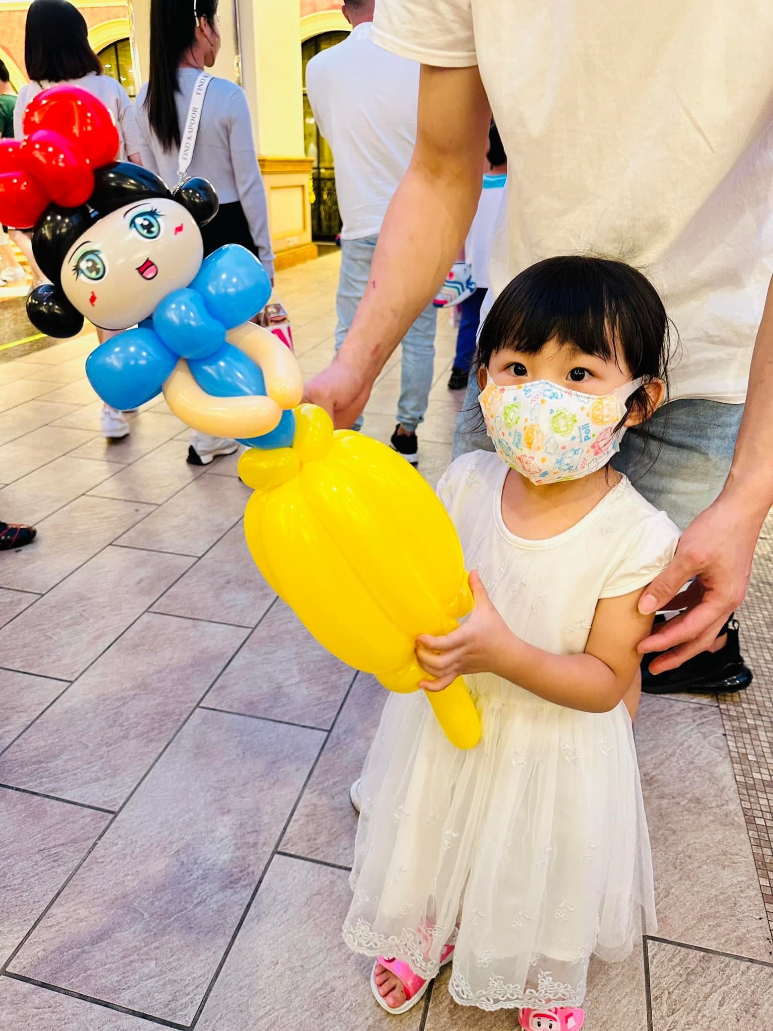 穿白色紗裙的小女孩抱著黑髮紅蝴蝶結、黃色裙子的白雪公主氣球