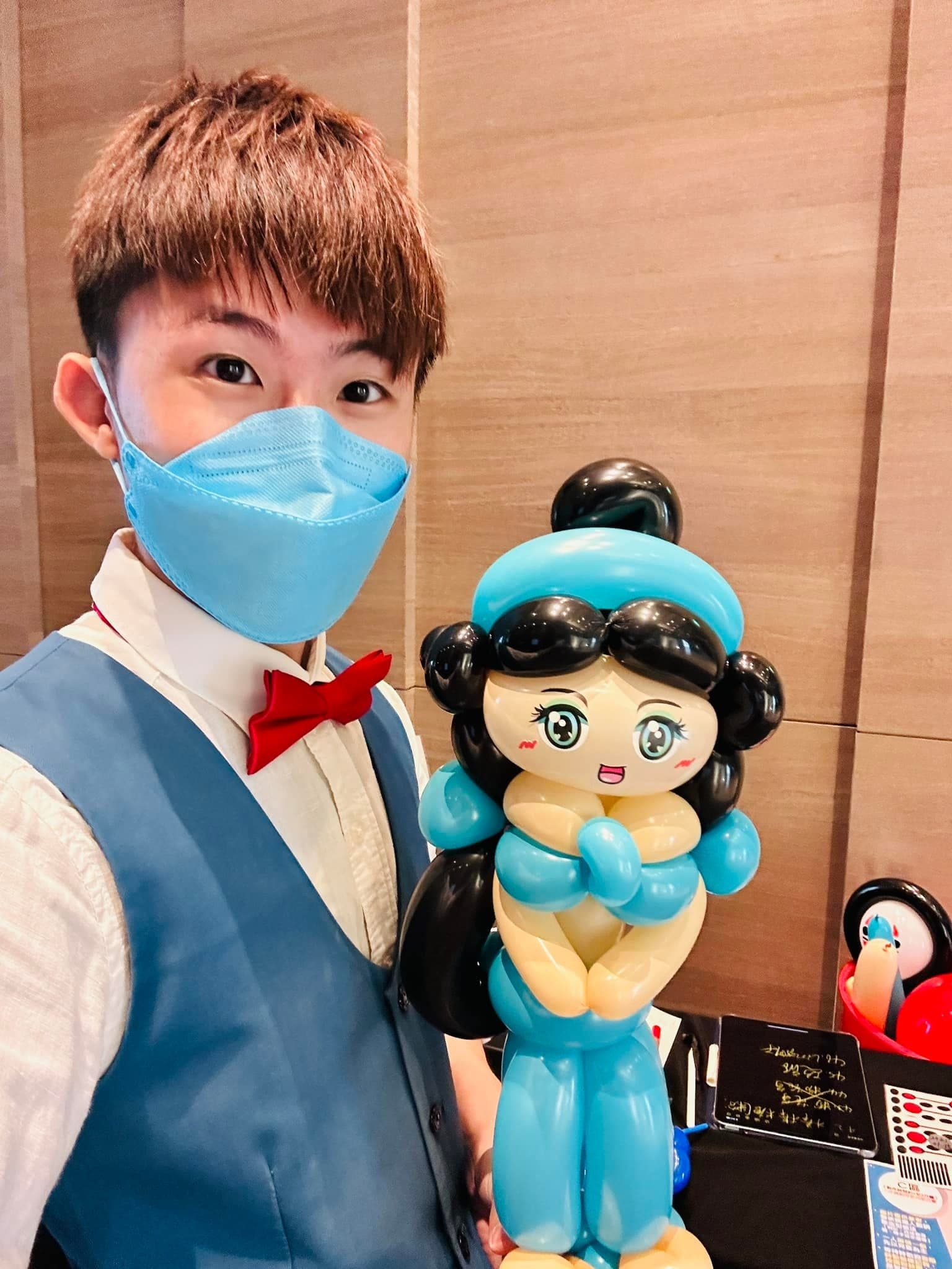我戴口罩自拍，手上拿著藍色衣服、黑色長髮的茉莉公主造型氣球