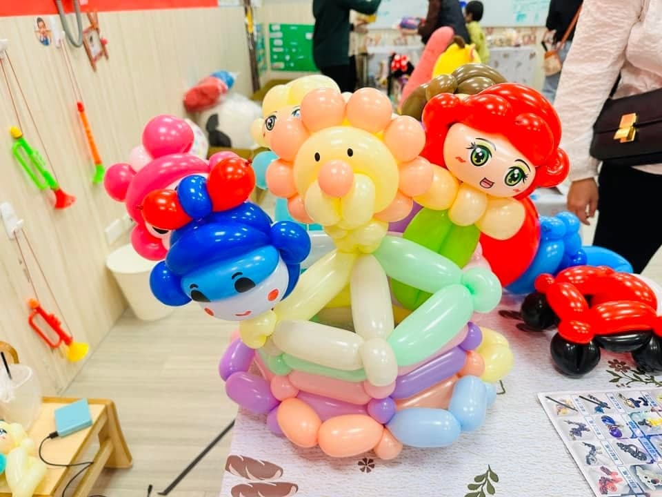 桌上的氣球花籃，圍著紅髮女孩、獅子與藍帽娃娃等角色臉