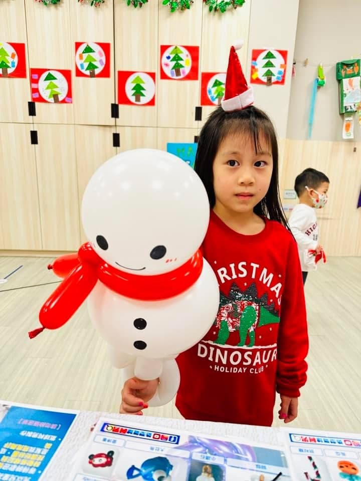 戴聖誕帽髮夾的小女孩拿著圍紅色圍巾的白色雪人氣球