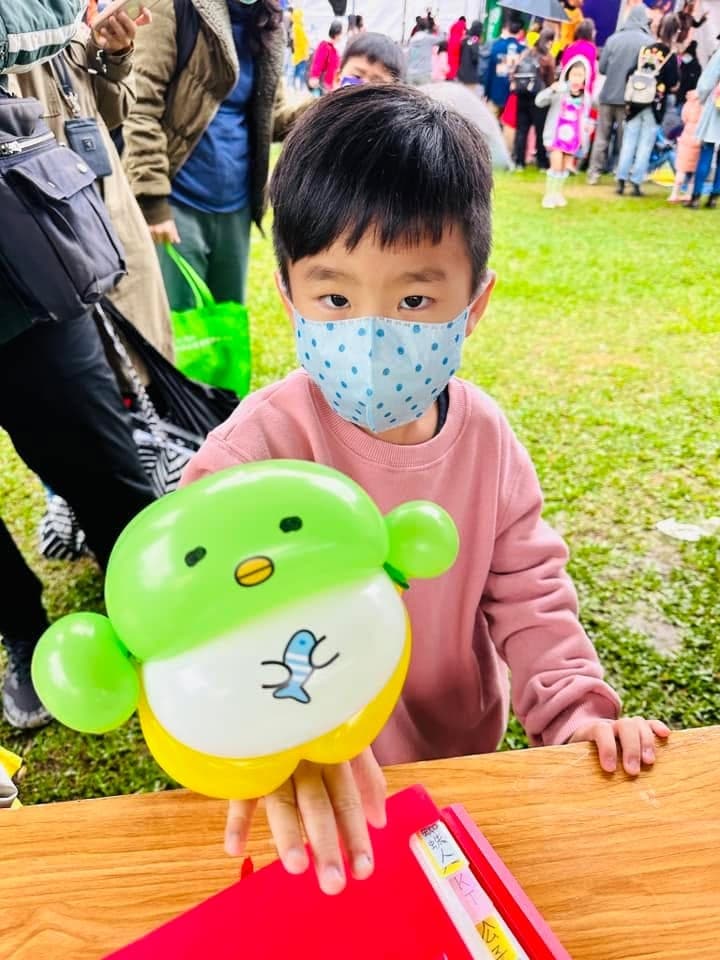 小男孩捧著淺綠色、肚子畫著小魚的企鵝造型氣球