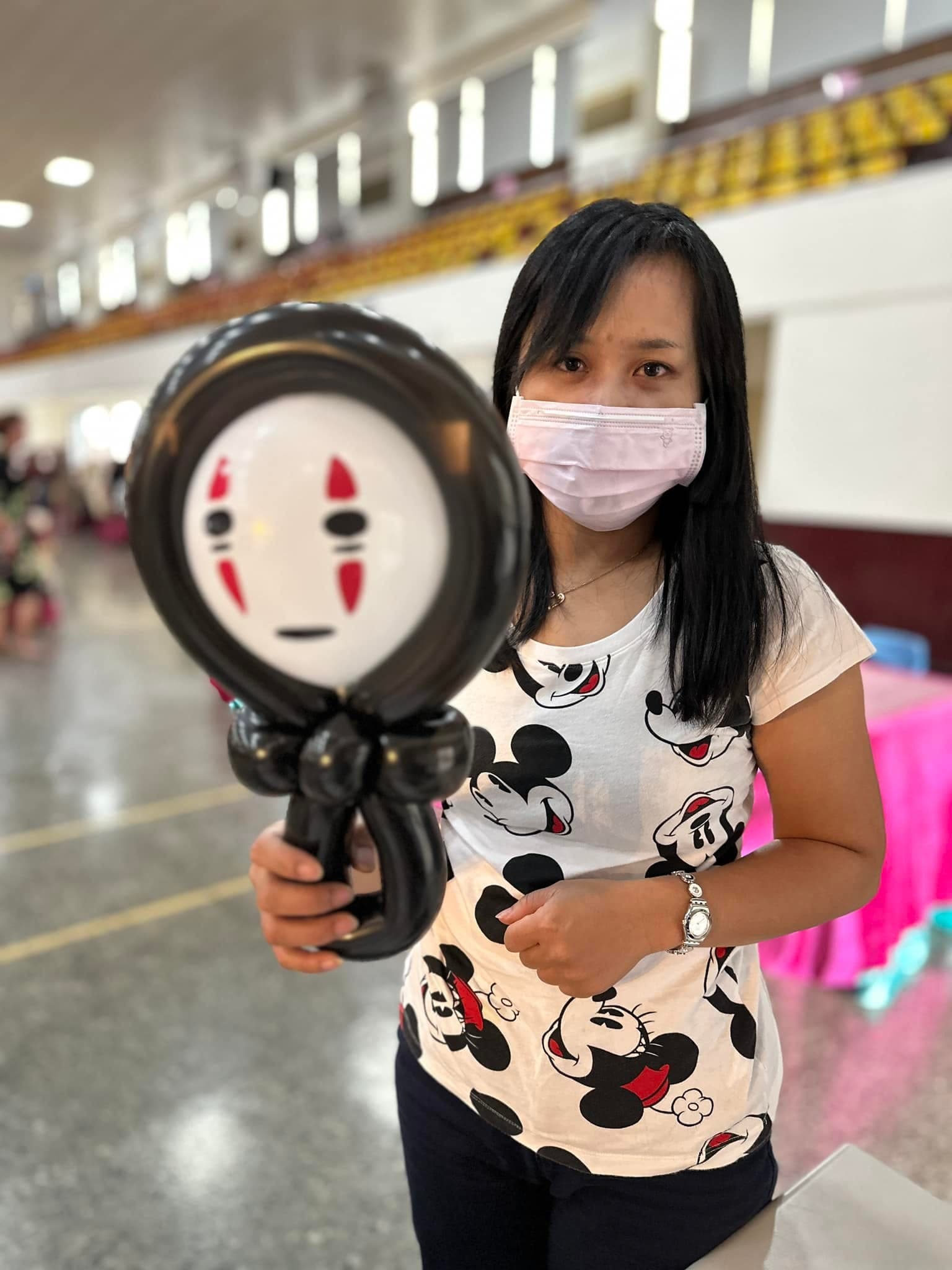女賓客拿著黑色外框、白色臉的無臉男造型氣球
