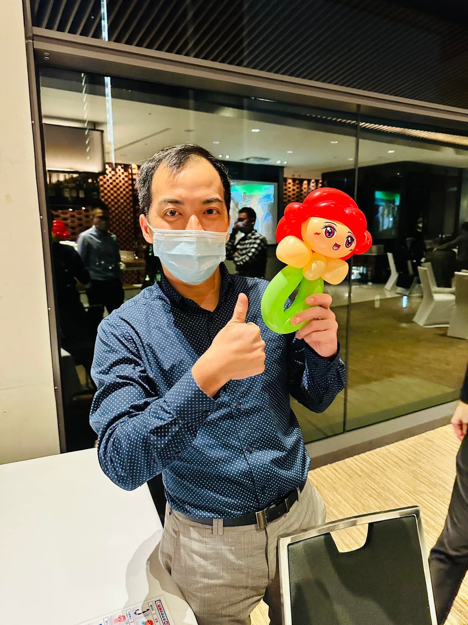 男賓客比讚，拿著紅髮綠尾巴的小美人魚造型氣球