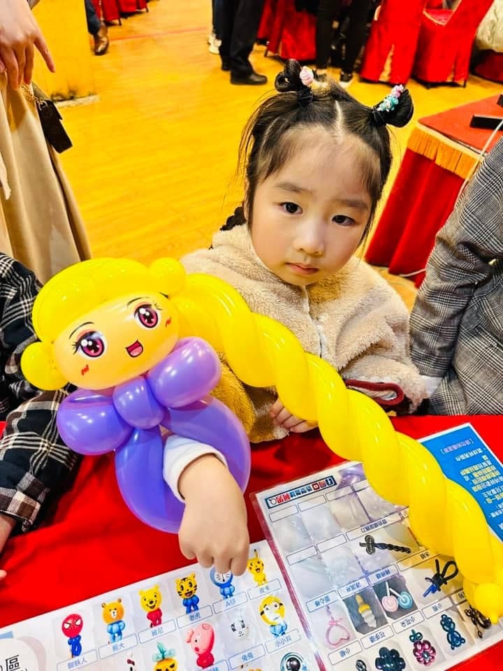 綁雙髻的小女孩抱著紫衣服、超長金色辮子的公主氣球