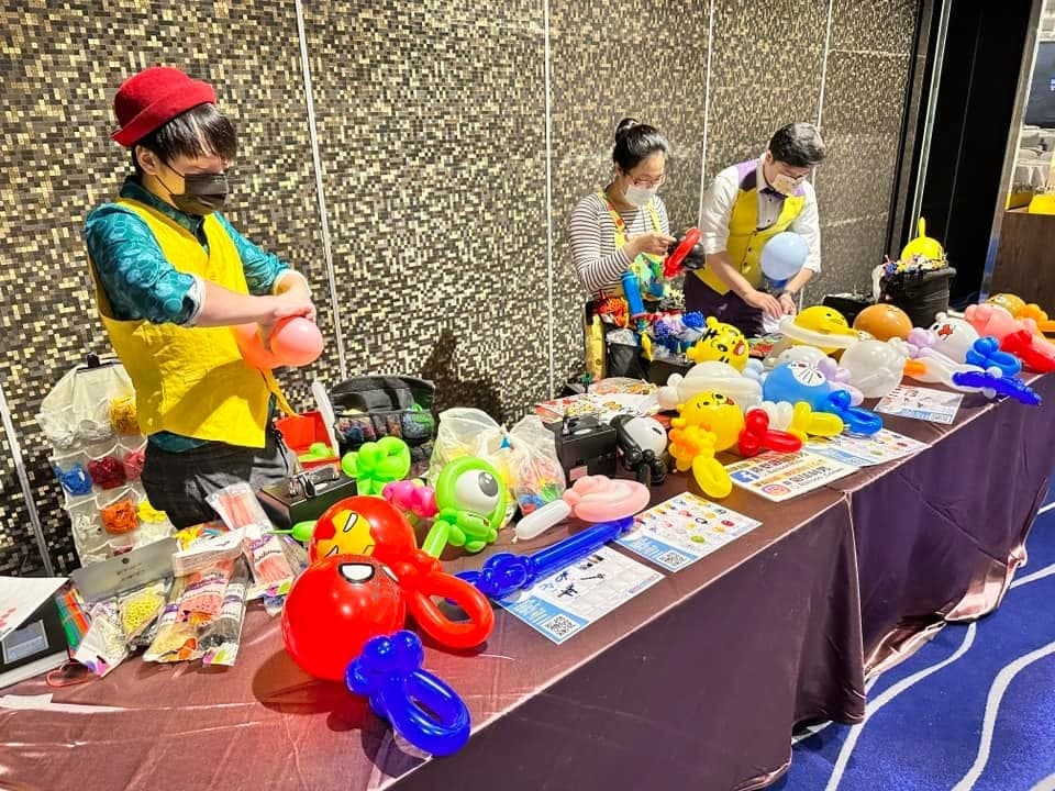 長桌上擺滿蜘蛛人、大眼怪、皮卡丘等造型氣球，氣球達人正在製作