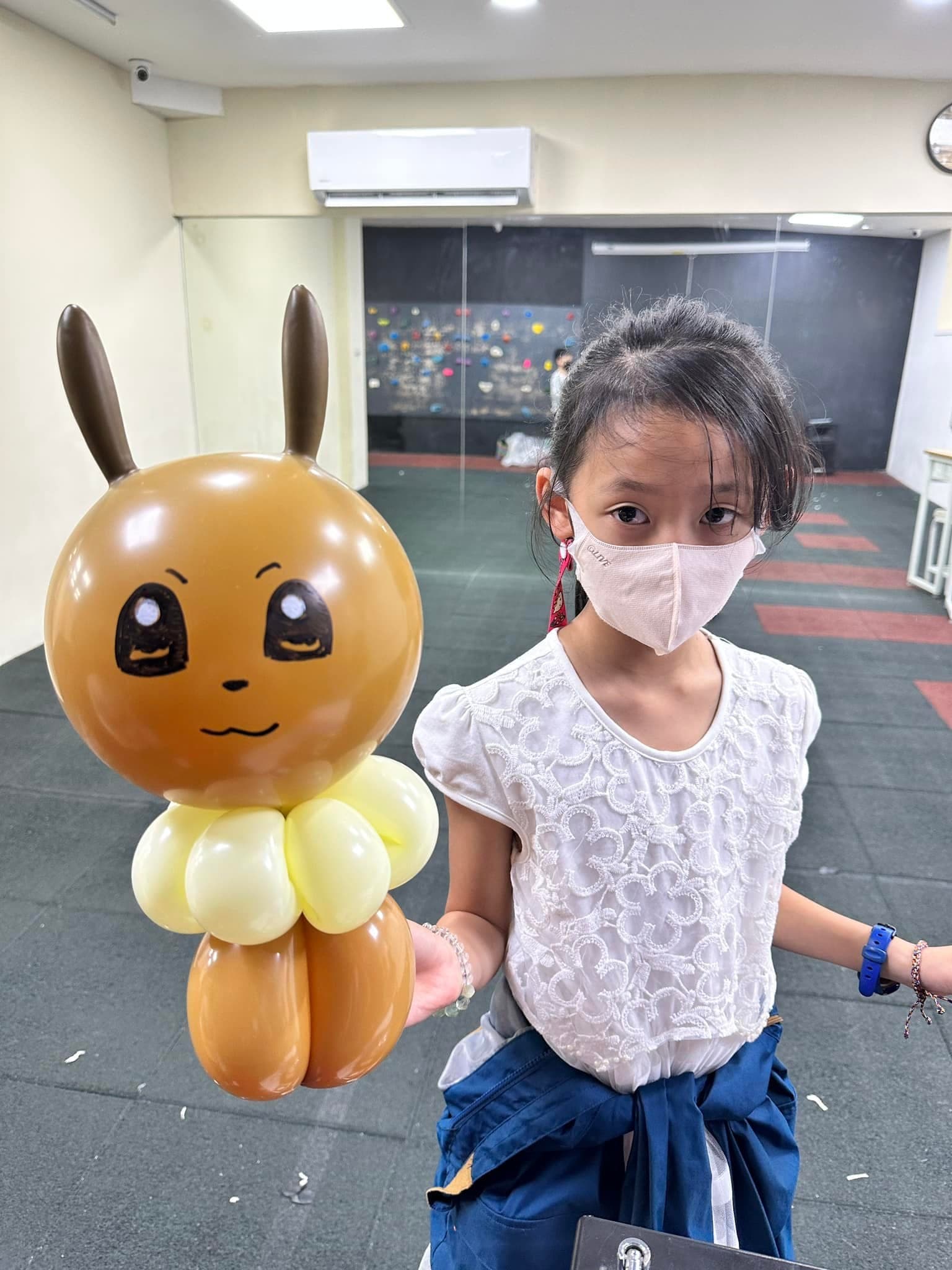女孩手上拿著咖啡色大耳朵、奶油色毛領的伊布造型氣球