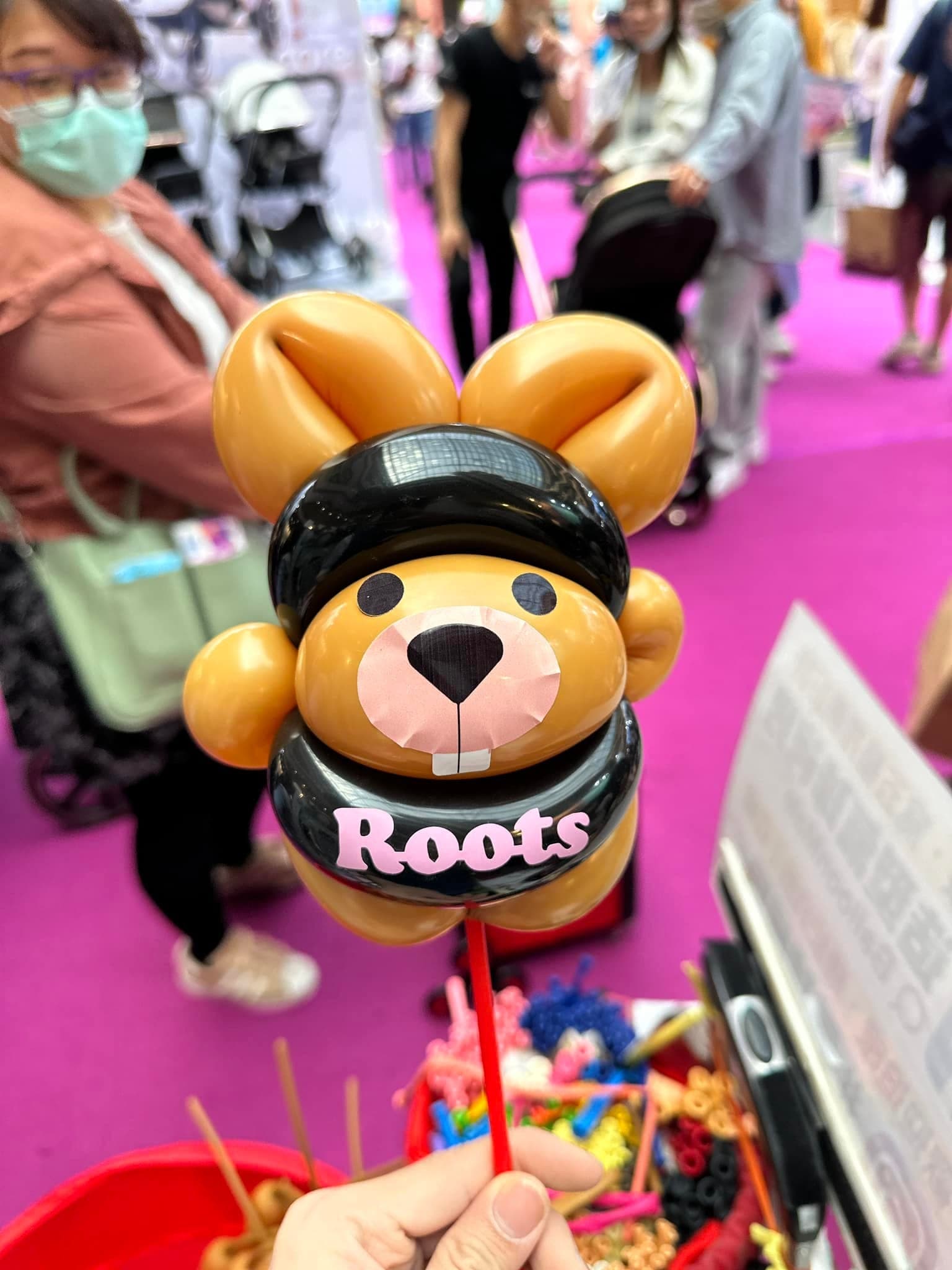 黑色帽子與圍巾、印著粉紅 Roots 字樣的海狸寶寶氣球近照