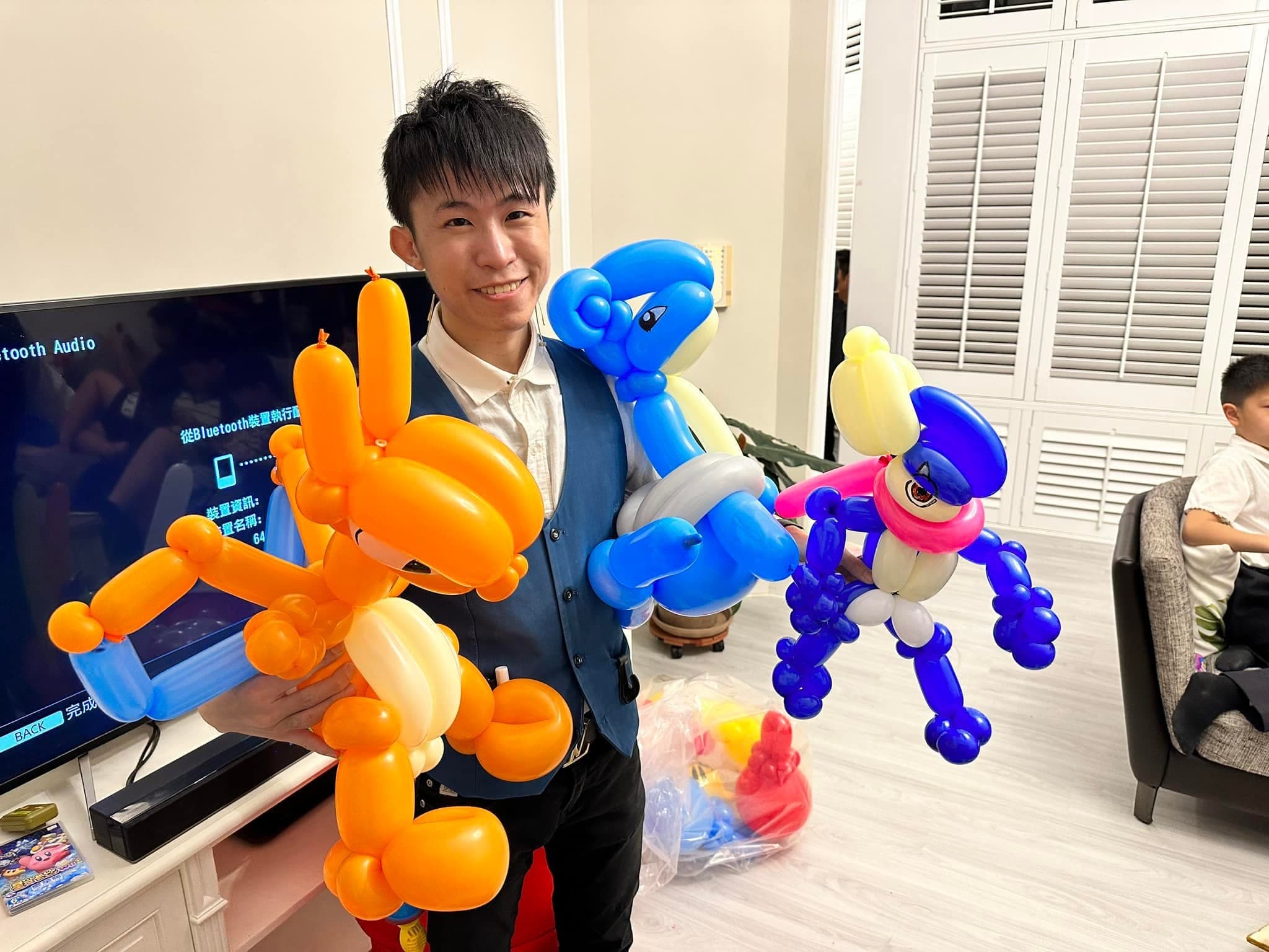 柯男手拿橘色噴火龍與藍色、紫色龍形造型氣球