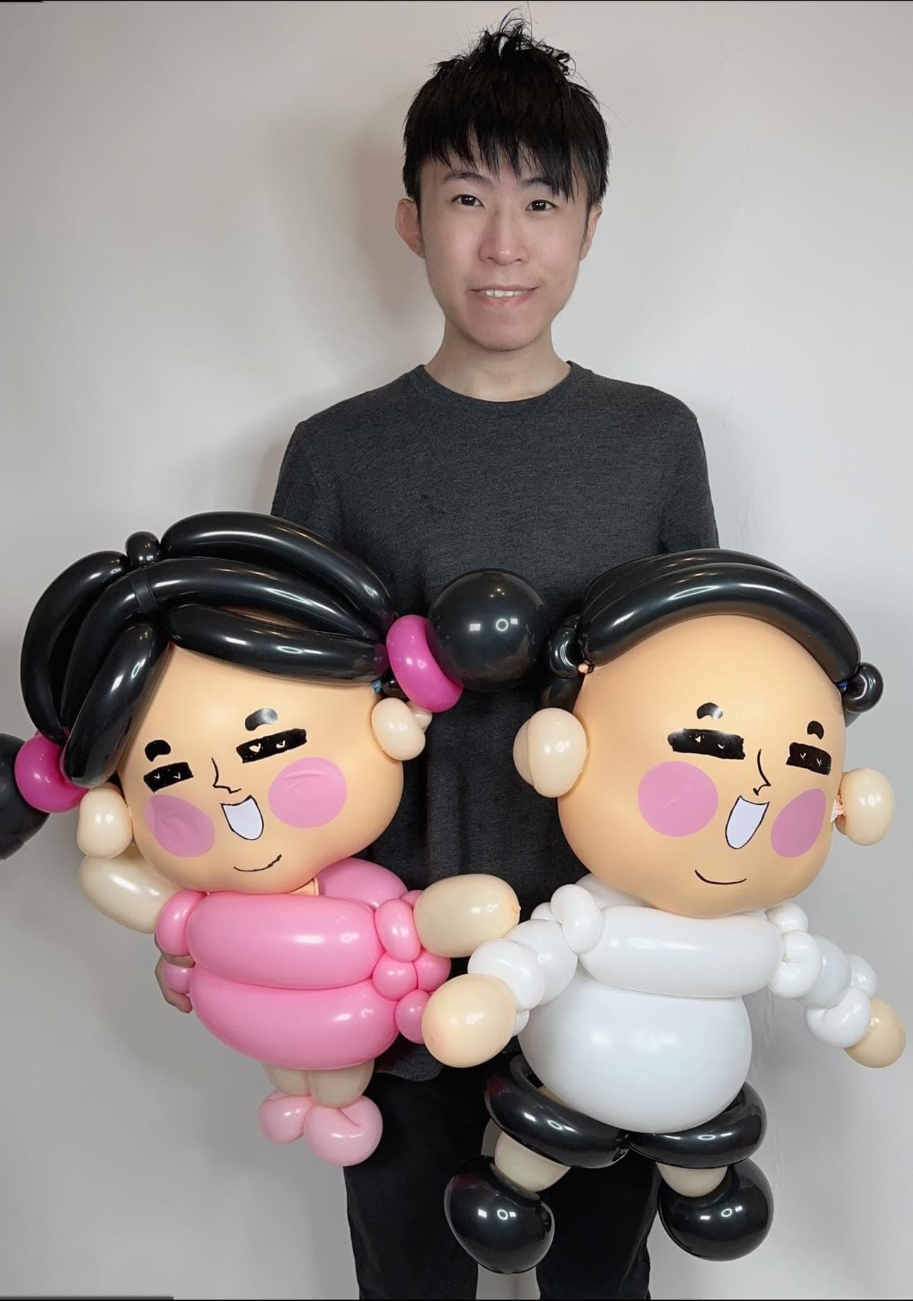 柯男抱著粉紅衣女生與白衣男生的達達與妃妃情侶氣球人偶