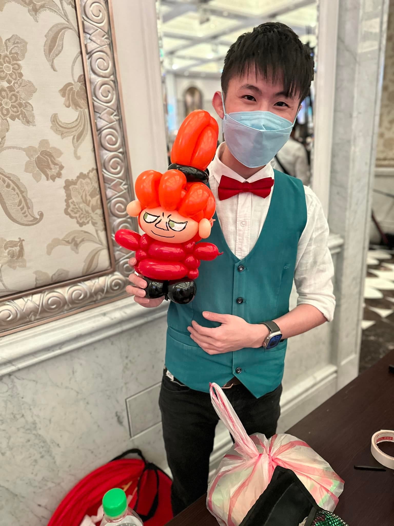婚禮會場裡，柯男拿著橘色髮髻、紅衣的小不點造型氣球