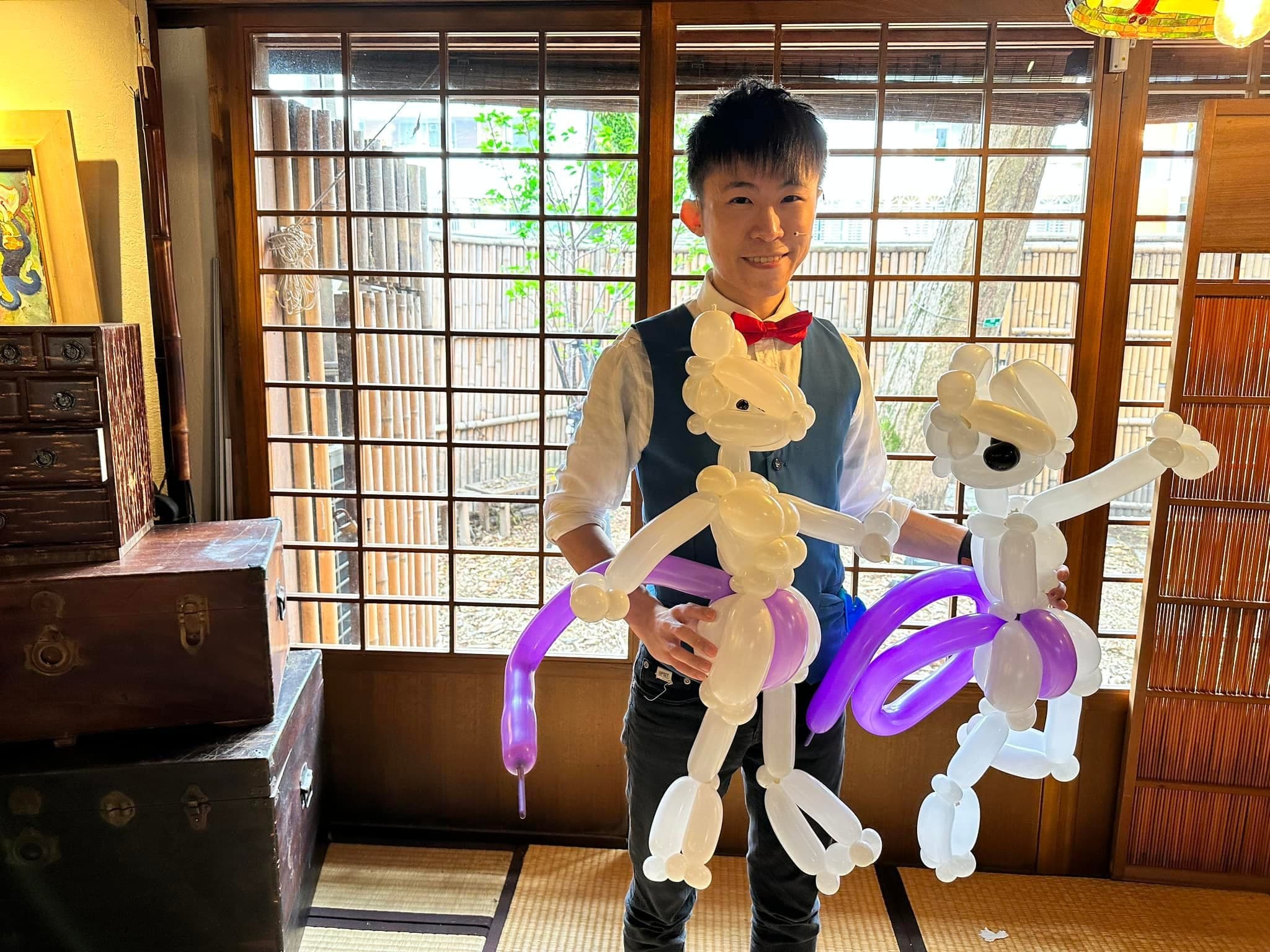 柯男雙手各拿一隻白色紫尾巴的超夢造型氣球