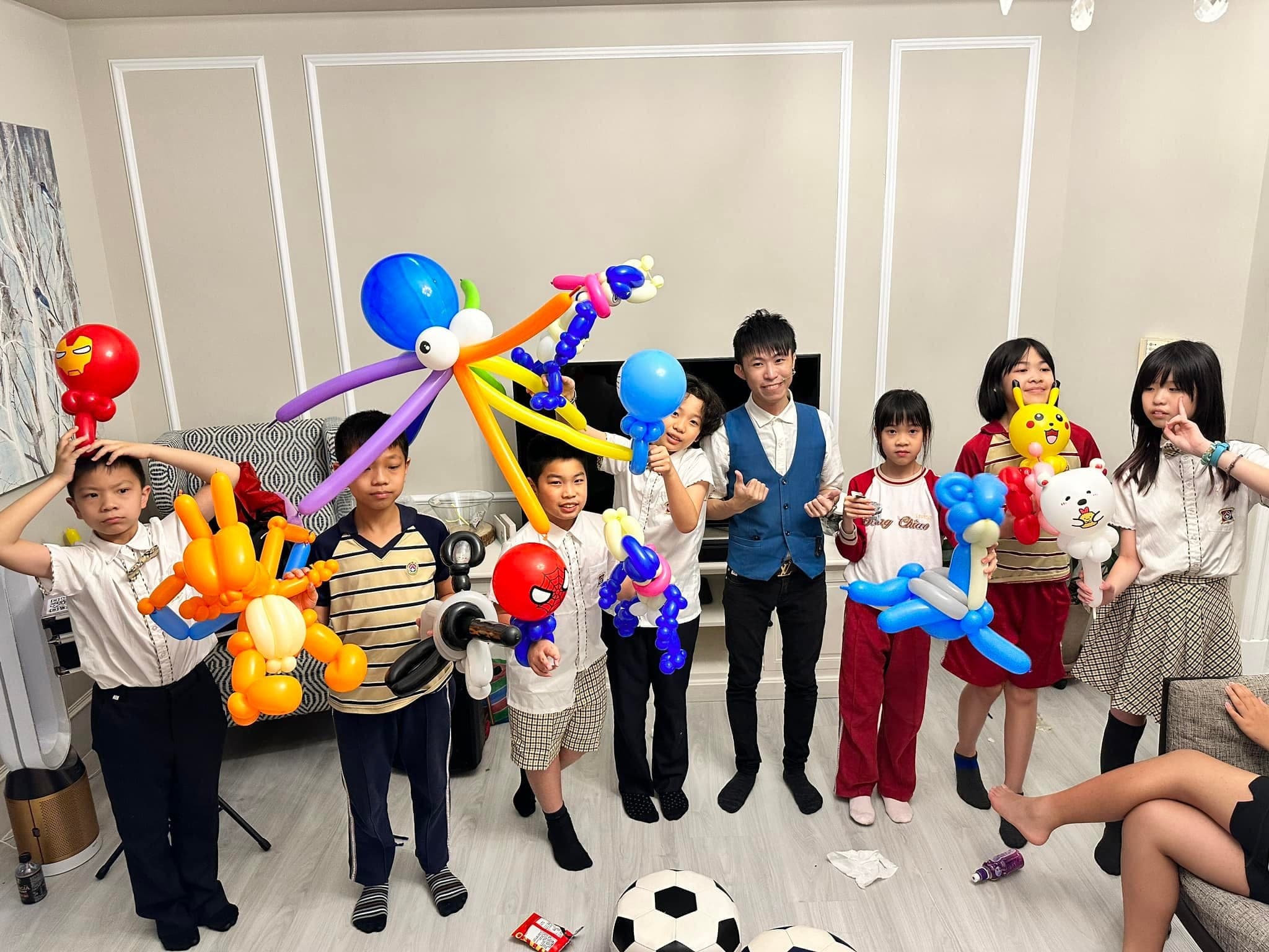 客廳裡的孩子們拿著章魚、噴火龍、蜘蛛人等氣球和柯男合照