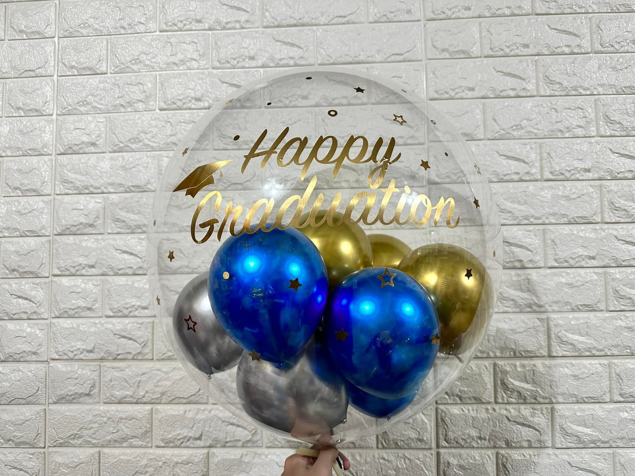燙金 Happy Graduation 字樣的透明波波球,內裝藍金銀小氣球