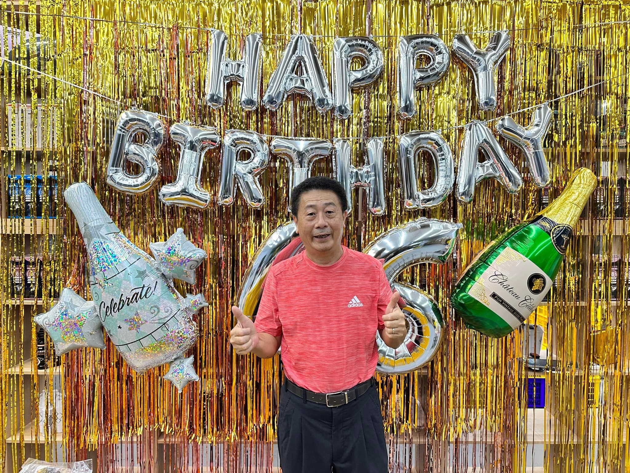 金色流蘇牆前掛著銀色 HAPPY BIRTHDAY 字母，兩側是香檳酒瓶鋁箔氣球