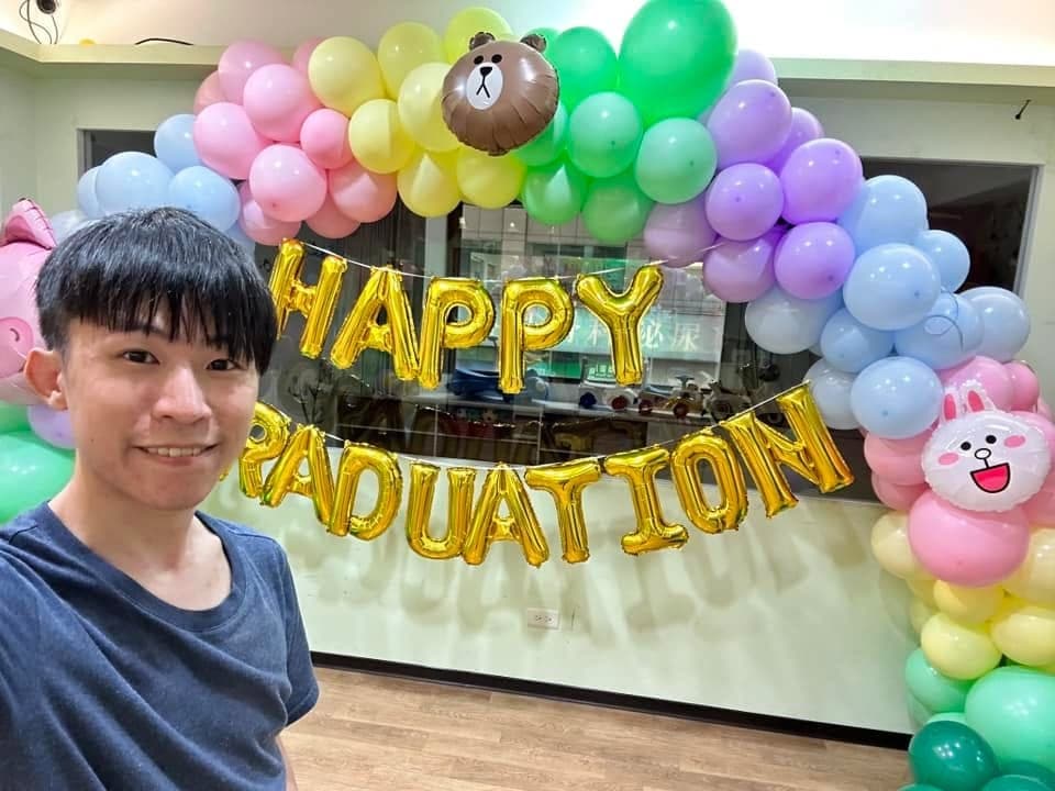 柯男在彩虹畢業拱門前自拍，拱門上有熊大與兔兔