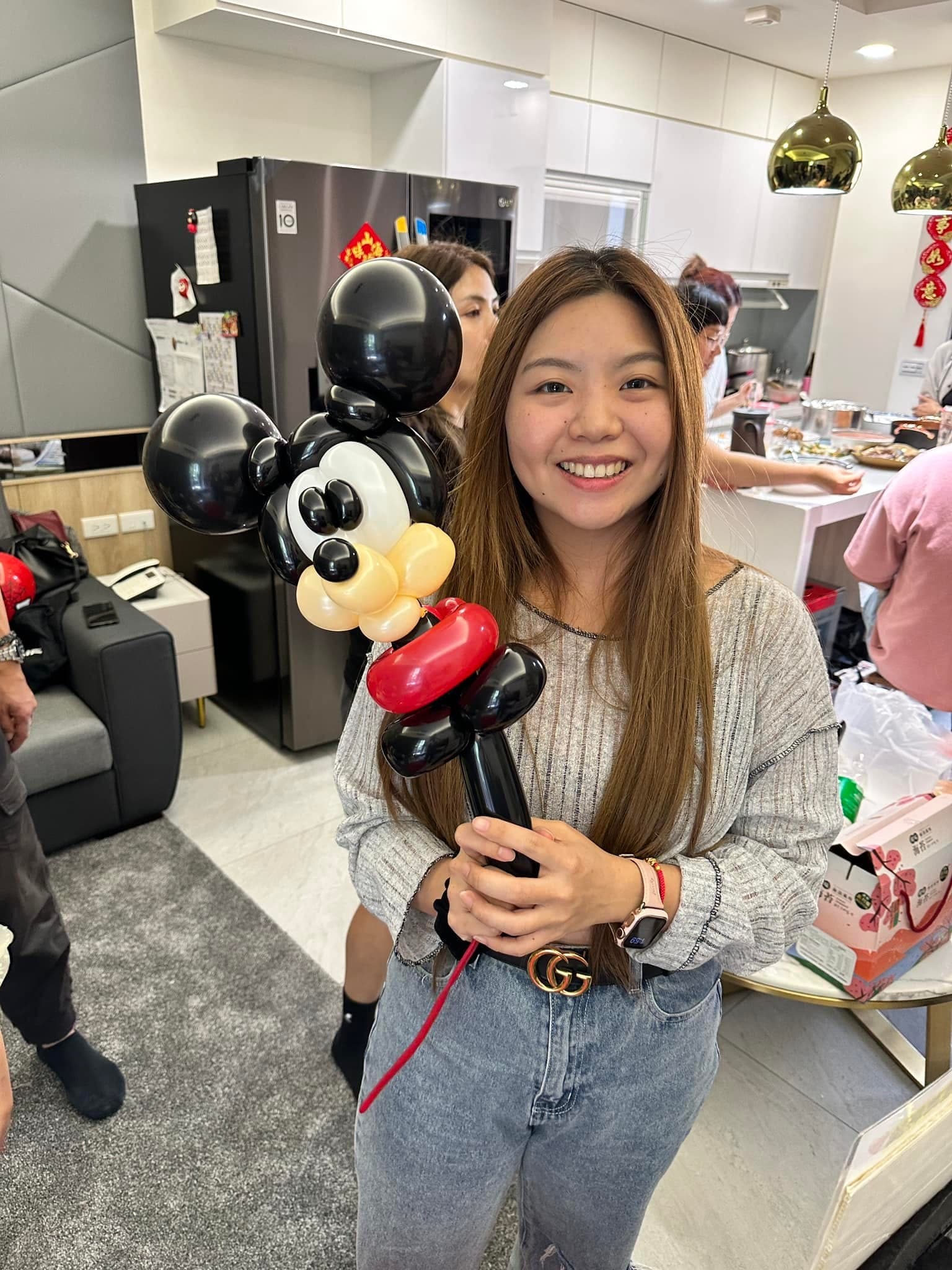 女賓客在廚房旁拿著米奇造型氣球微笑