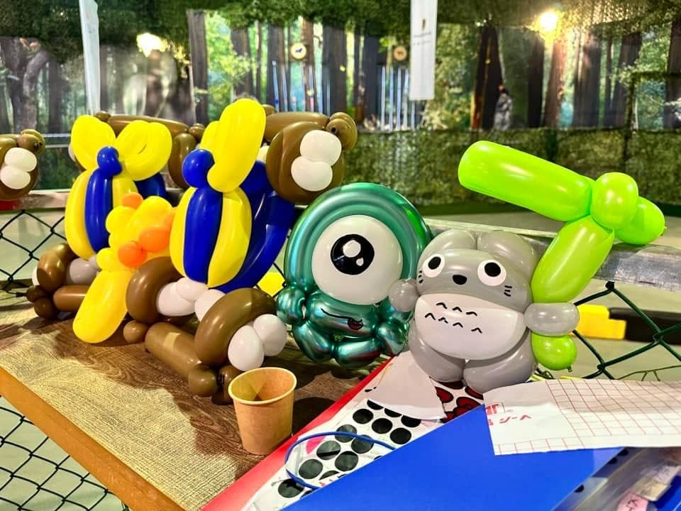 桌上排著龍貓、綠色獨眼角色和抱著蜜蜂的小熊造型氣球