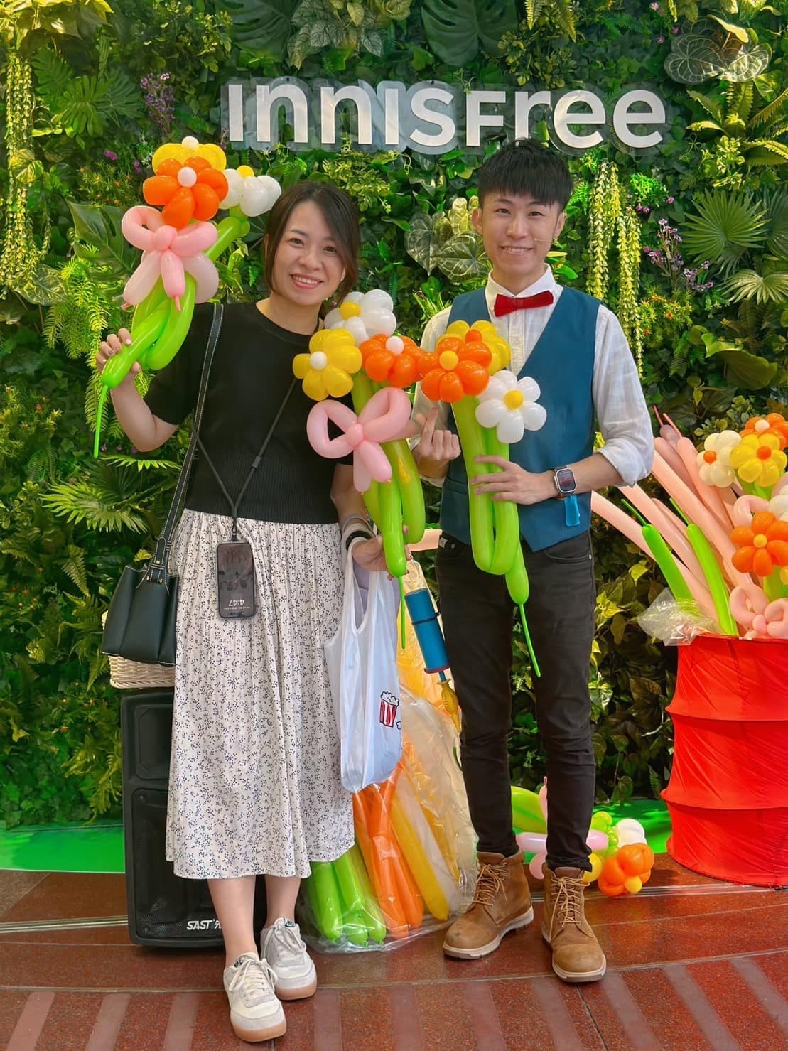 民眾和柯男在 innisfree 招牌下合照，各自拿著花朵氣球花束