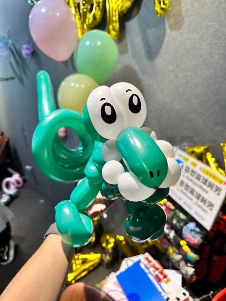 綠色金屬光澤的小恐龍造型氣球，大眼睛、捲尾巴