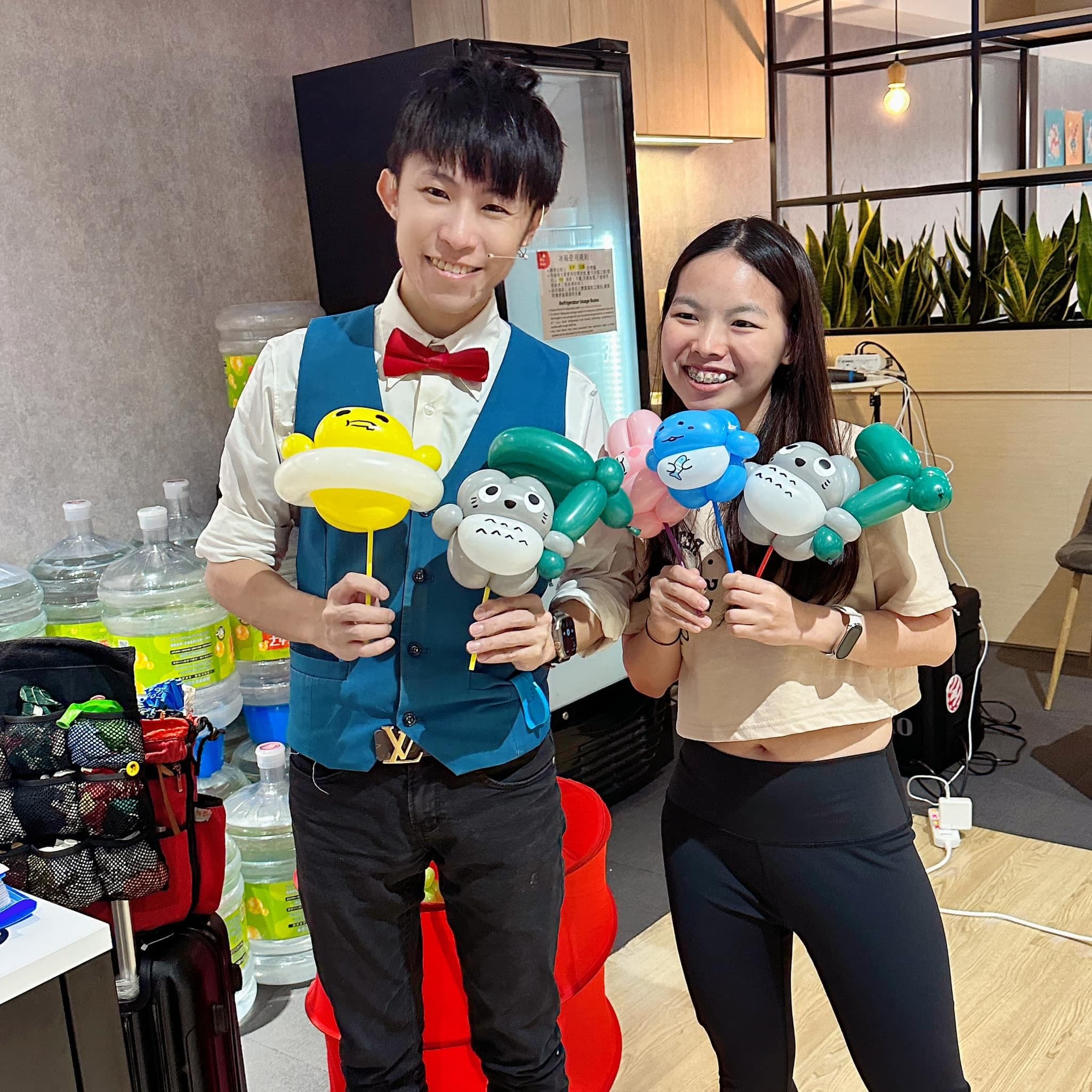 柯男與女生各拿著龍貓、蛋黃哥與藍色角色的棒棒小造型氣球合照