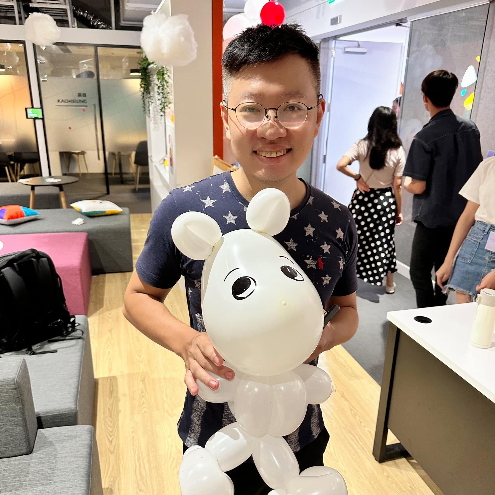 戴眼鏡的男生抱著白色圓耳朵、長鼻子的角色造型氣球