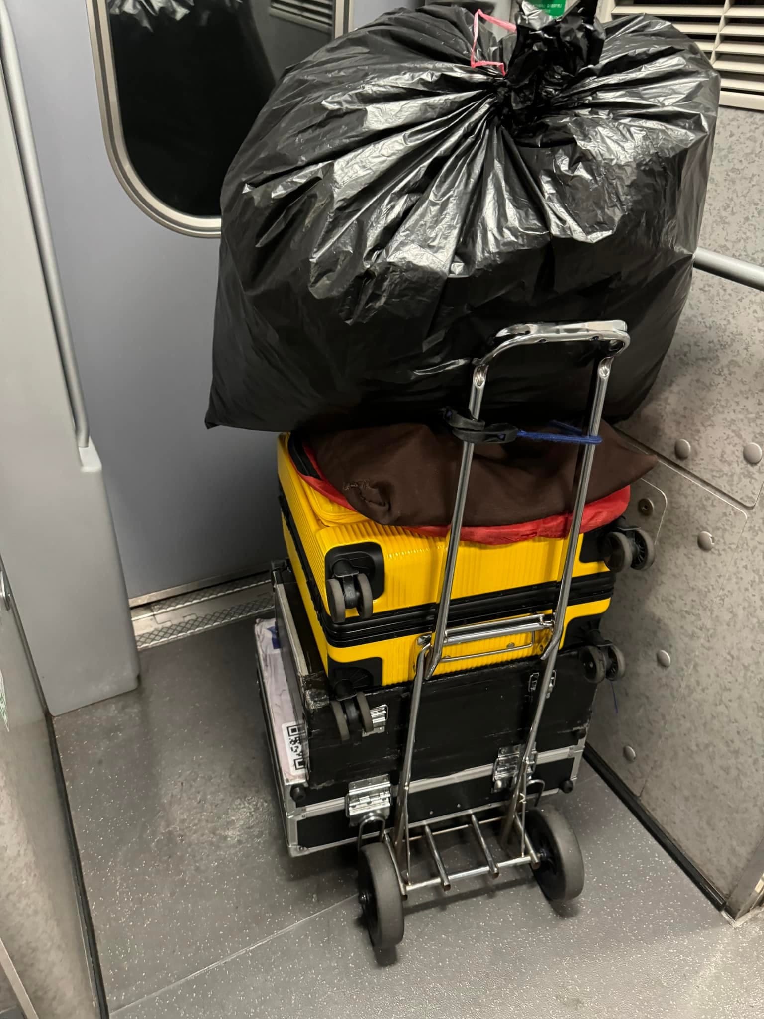高鐵車廂裡，推車上疊著行李箱和一大袋黑色垃圾袋裝的氣球