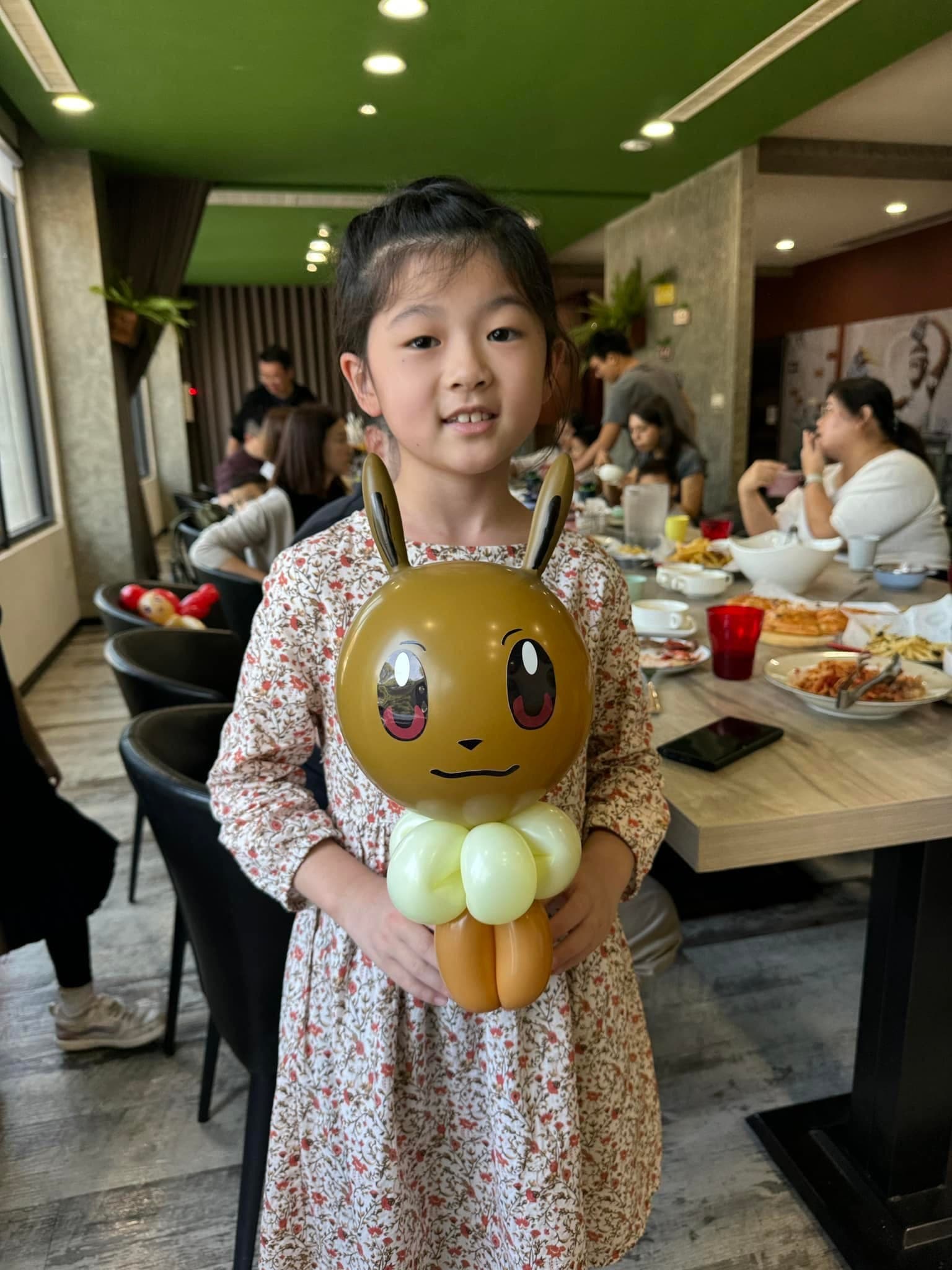 女孩在餐廳裡抱著咖啡色伊布造型氣球