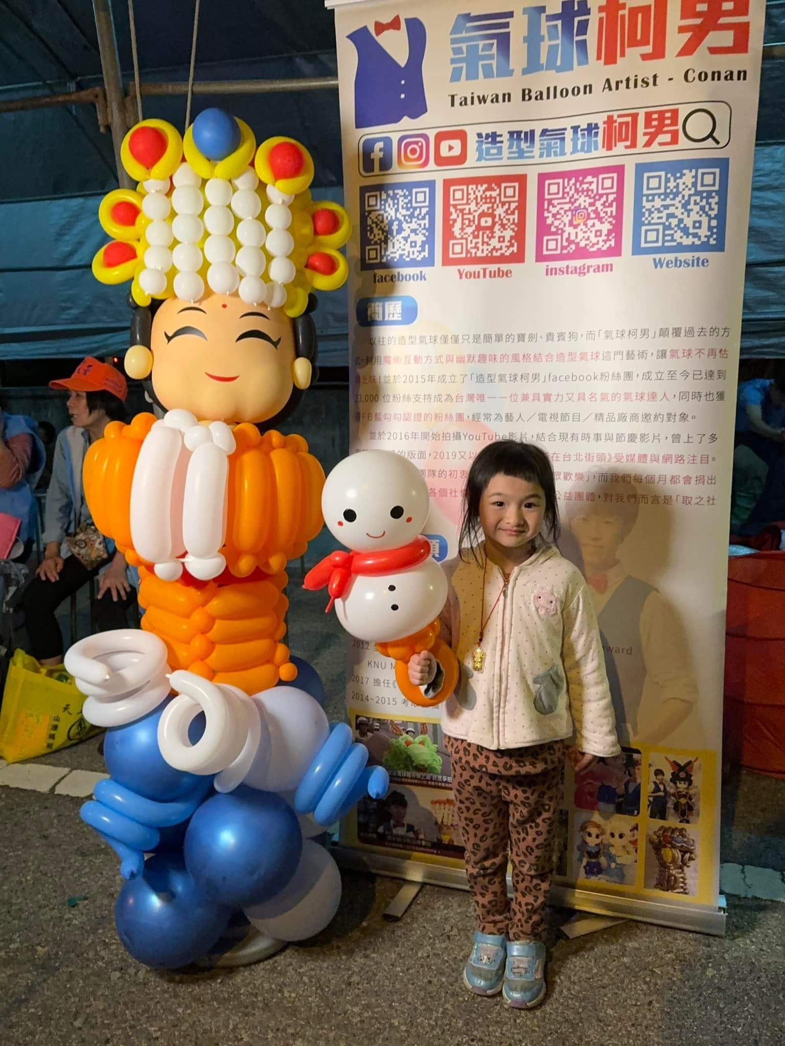小女孩拿著雪人造型氣球，和氣球媽祖站在一起合照