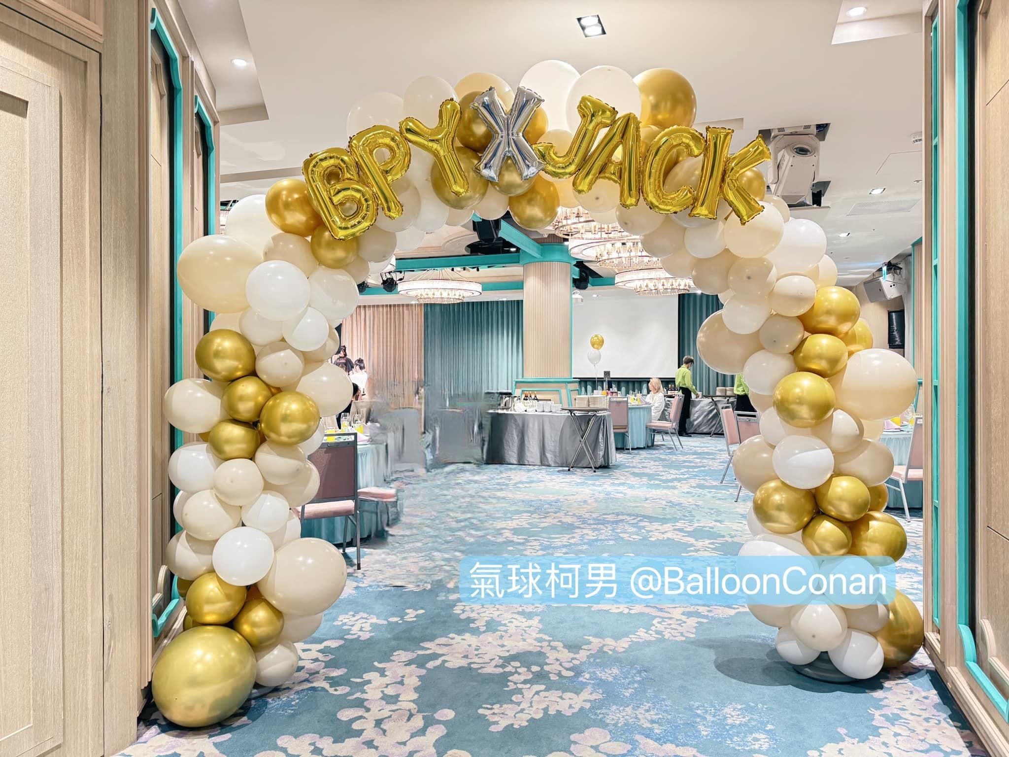 宴會廳入口的奶油白與金色氣球拱門，上方掛金色字母氣球